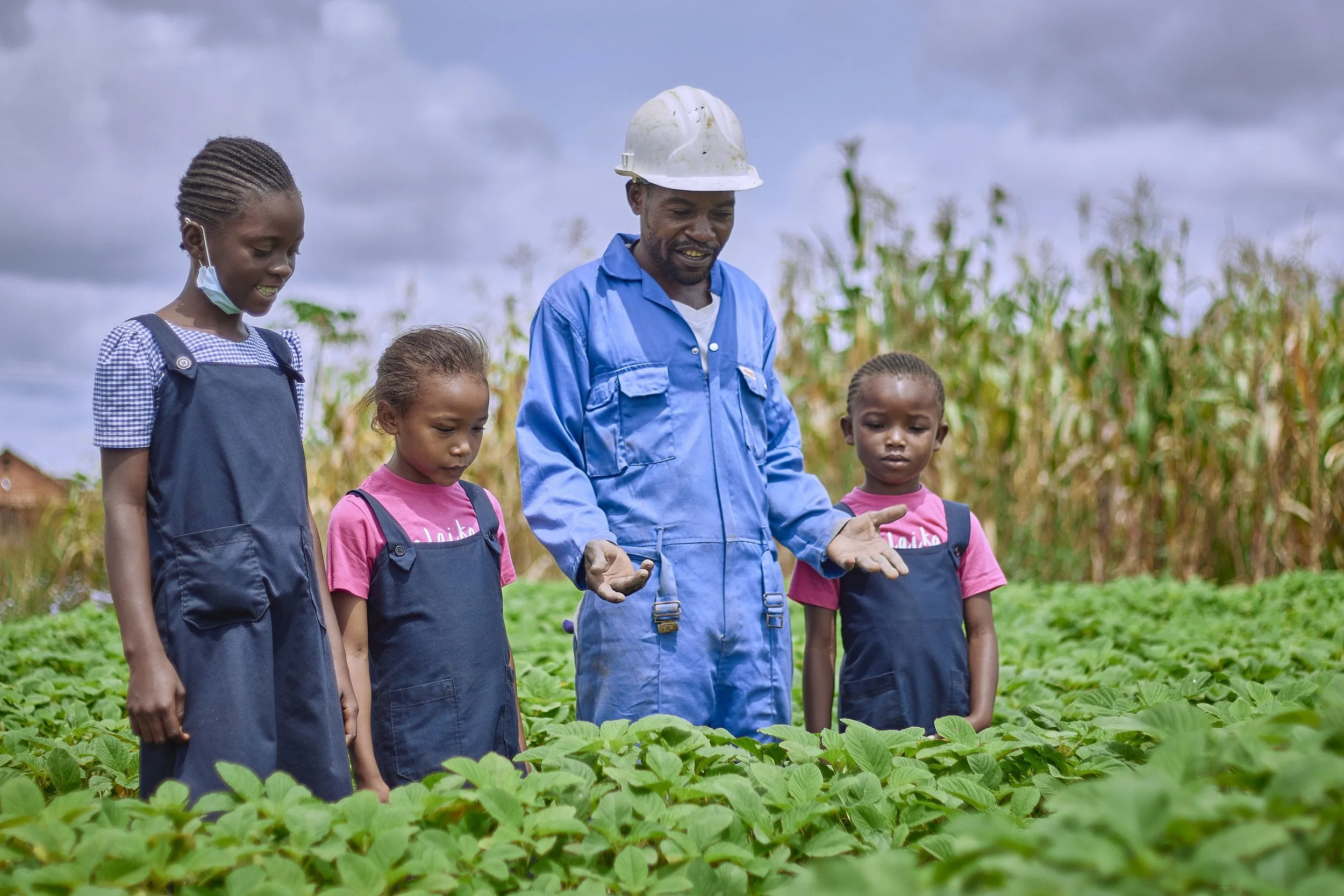 Adult man with local youngsters looking at vegetation. 