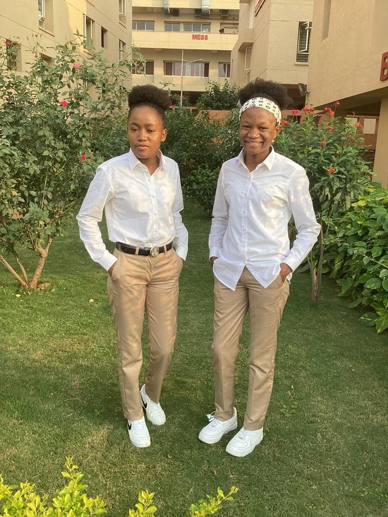 Louise at the age of 20 with another Malaika student both wearing a white shirt and brown pants.