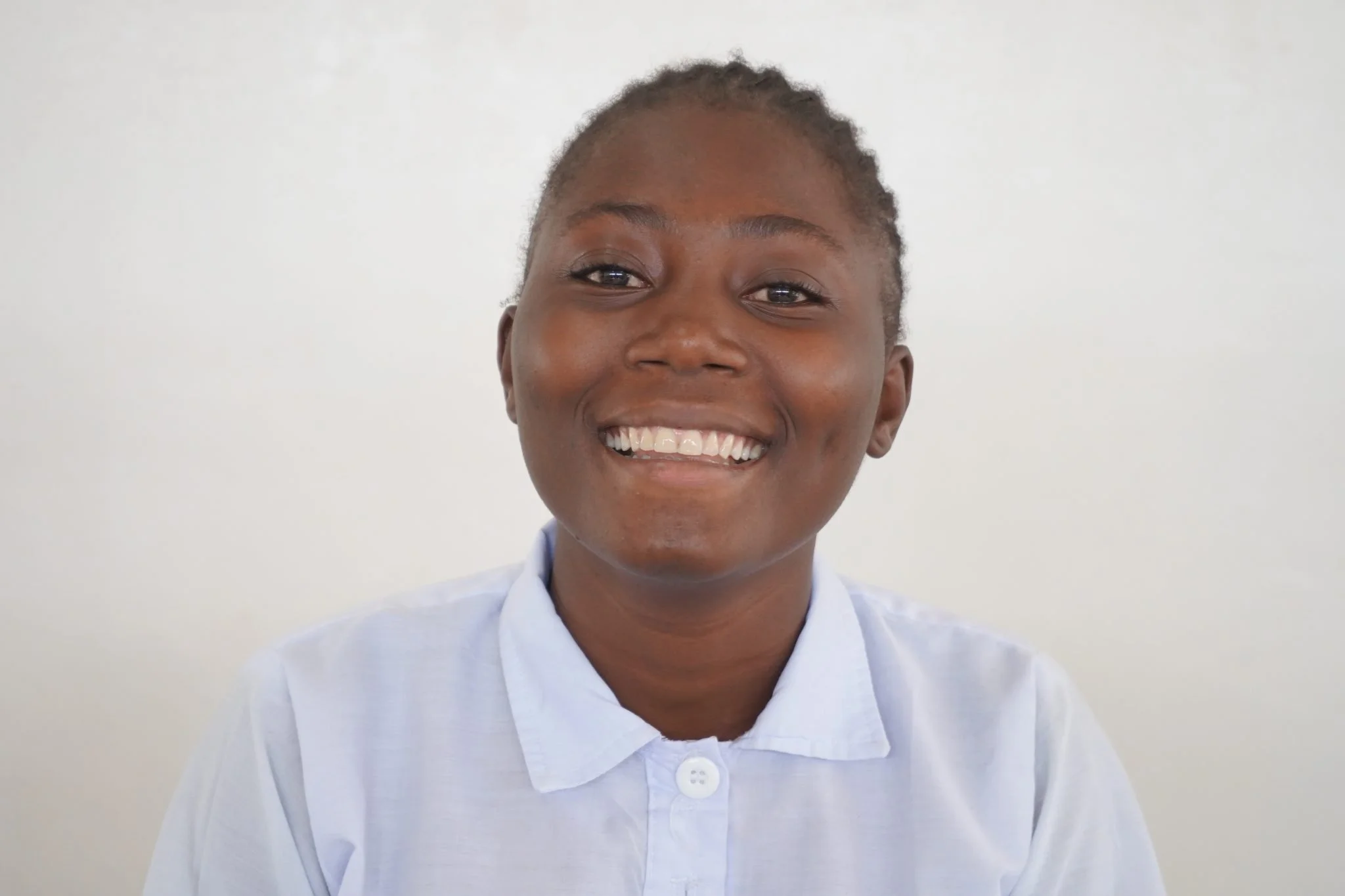 Marie smiling at the camera wearing a white school uniform.