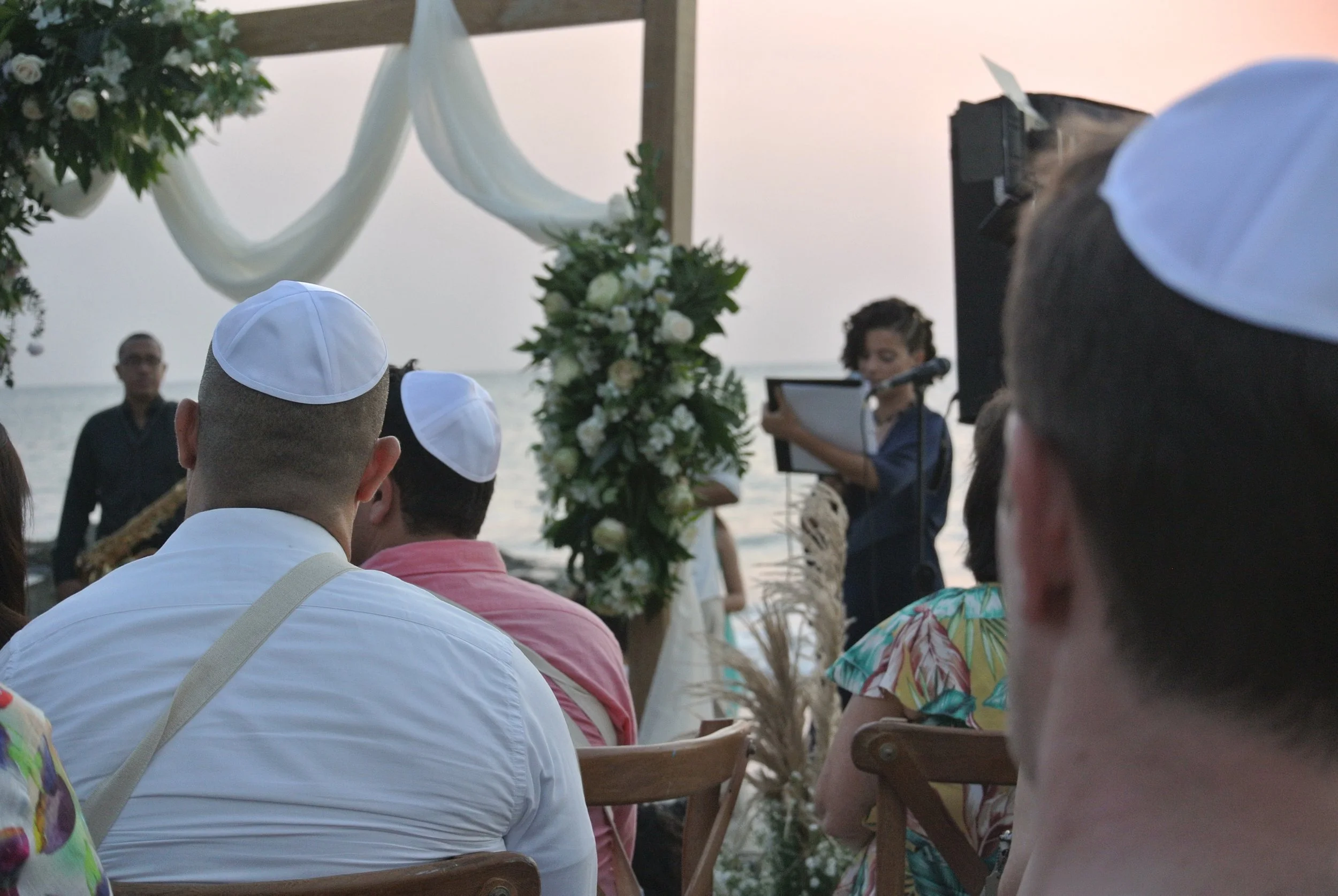 Multicultural ceremony guests wearing kippahs during an intentional destination union blending diverse traditions at Blue Apple Beach in Cartagena by Bel Altar.