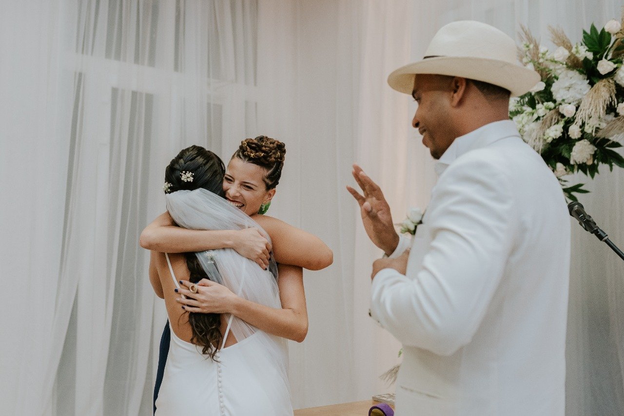 Bel Altar officiant and bride hugging after the proclamation of the ceremony while the groom happily greets their guests.