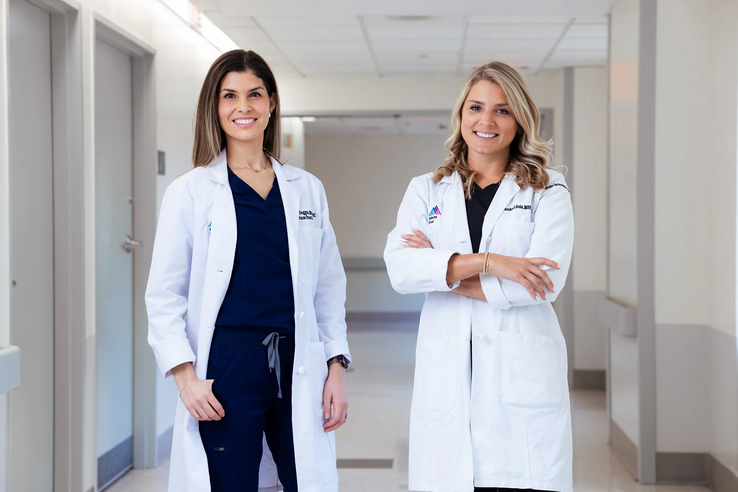 Two doctors in white coats standing in a hospital hallway.