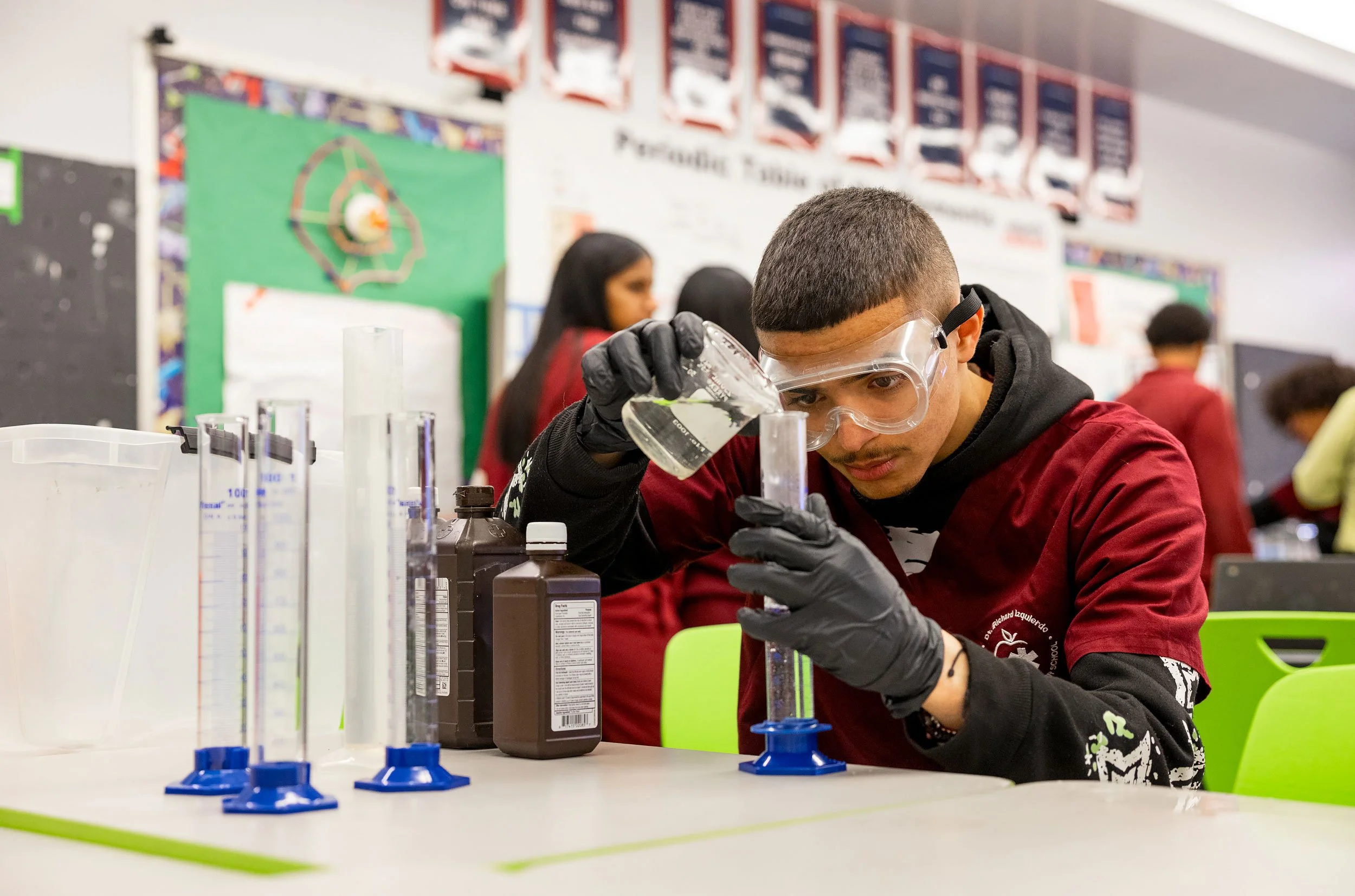 Student focused on science experiment using equipment in classroom lab.