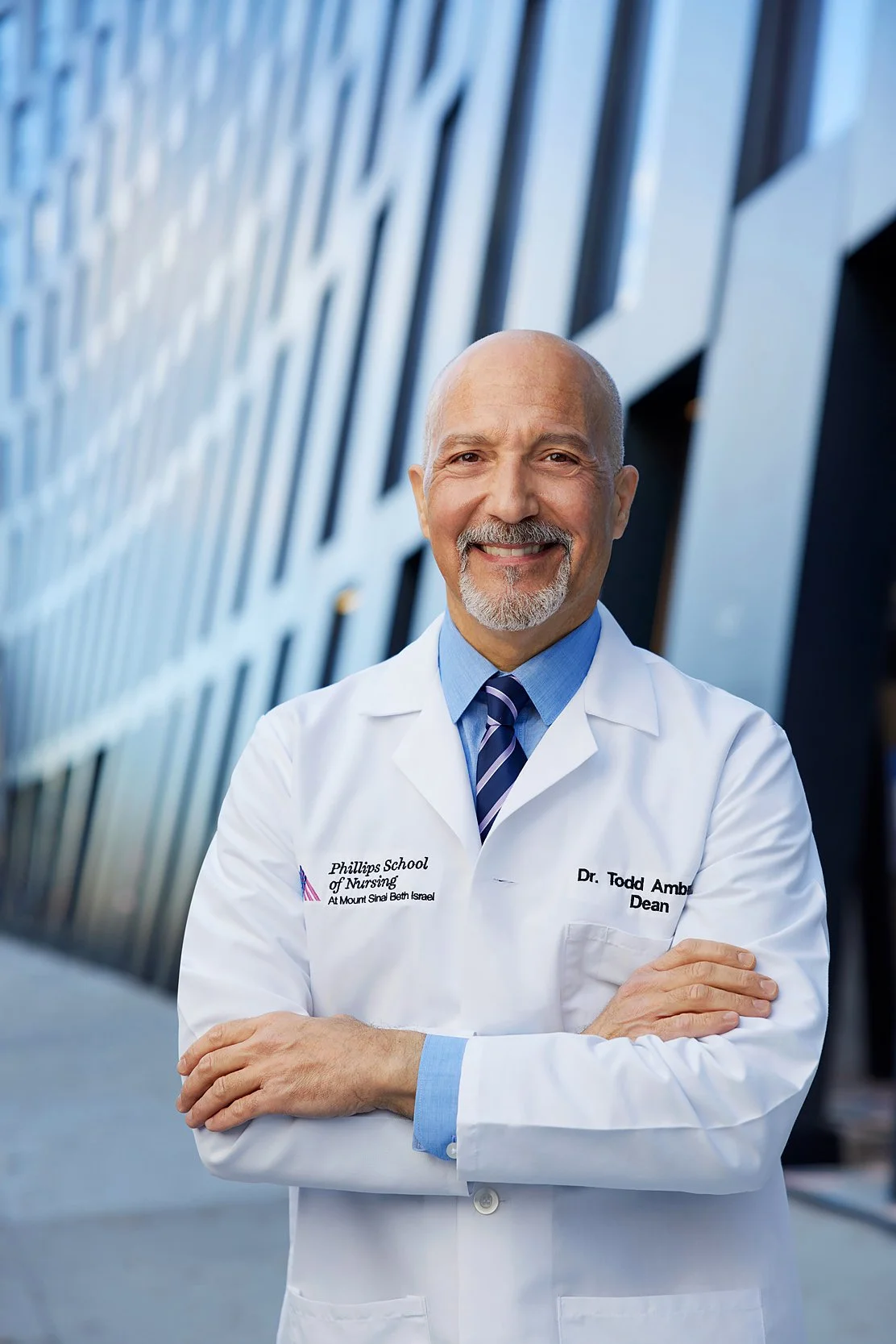Confident male doctor standing outdoors in front of a modern building.