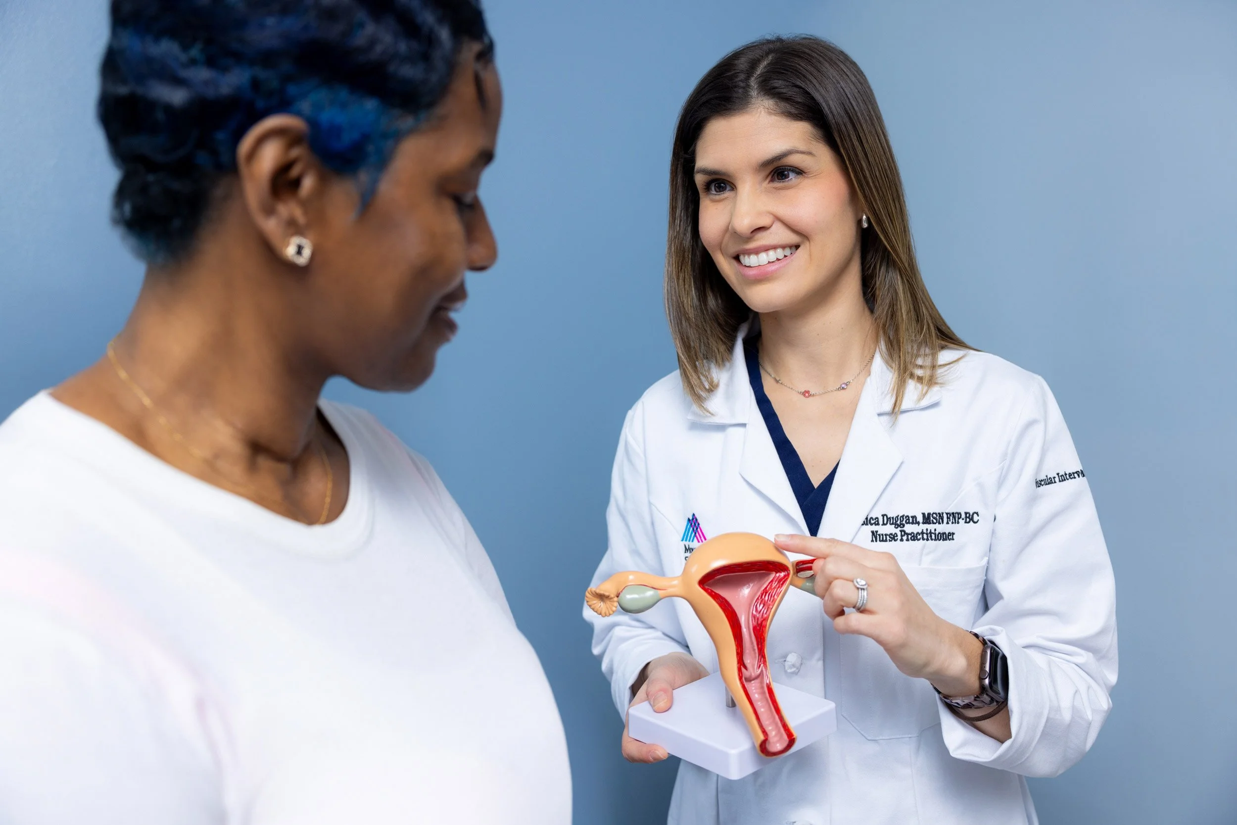 Female doctor showing a medical model of a uterus to a patient.