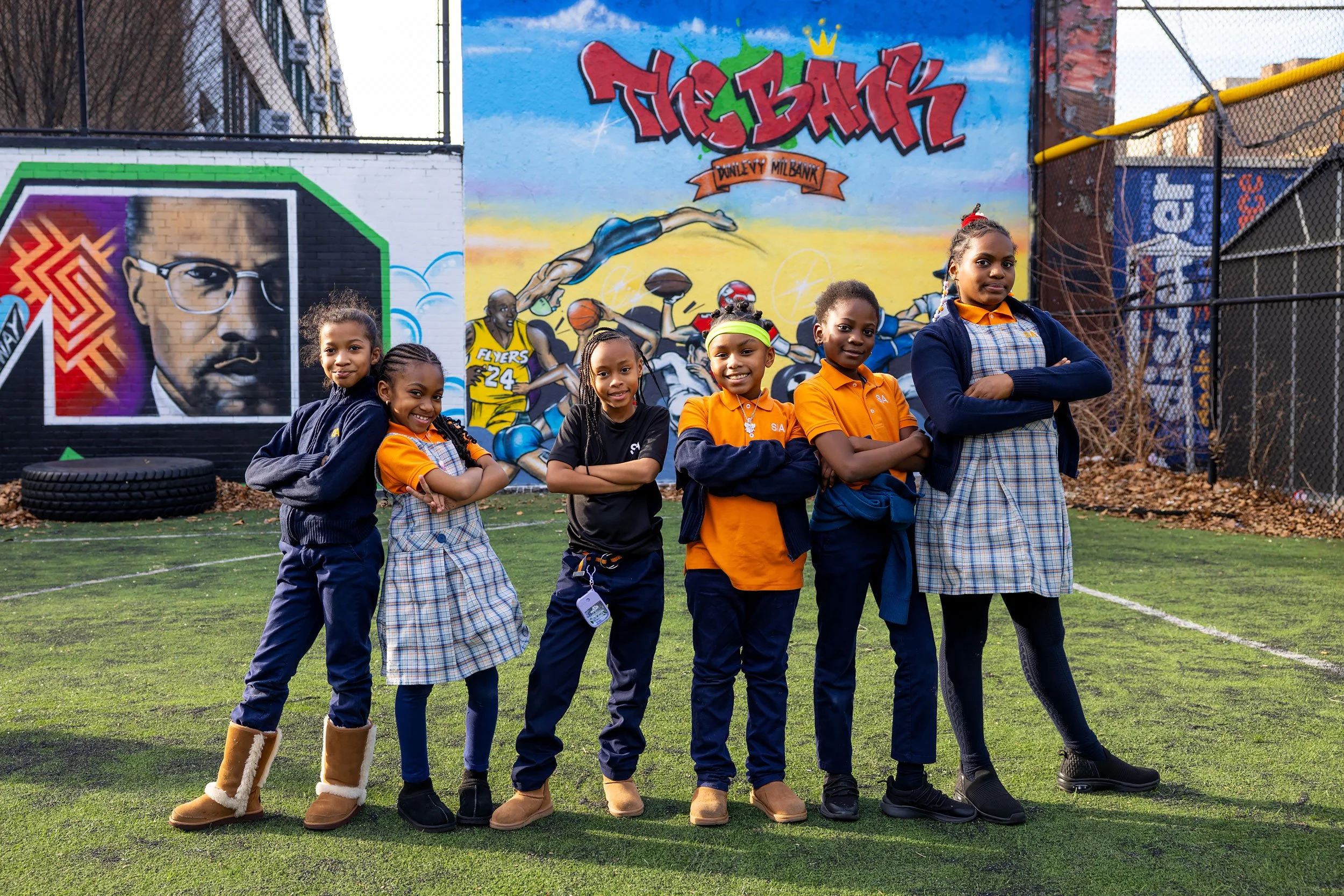 Group of students in uniforms standing together outside on a school playground, posing as a team.

