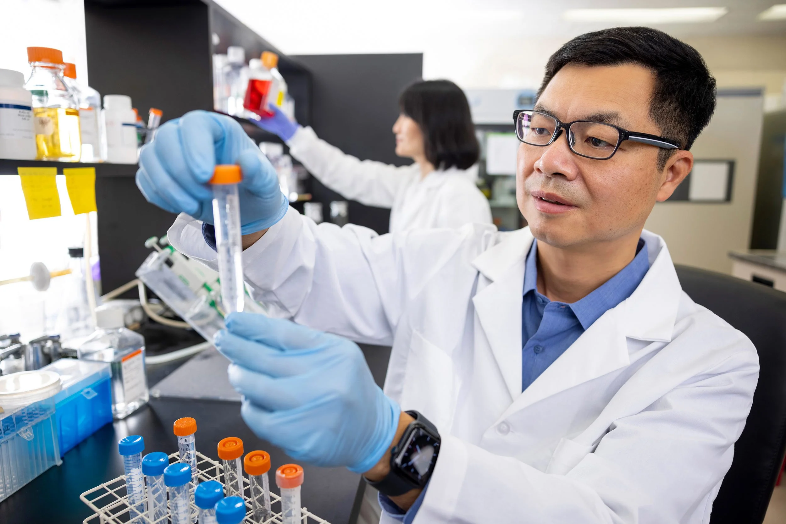 Two scientists, one male one female pipetting liquid in a research lab.