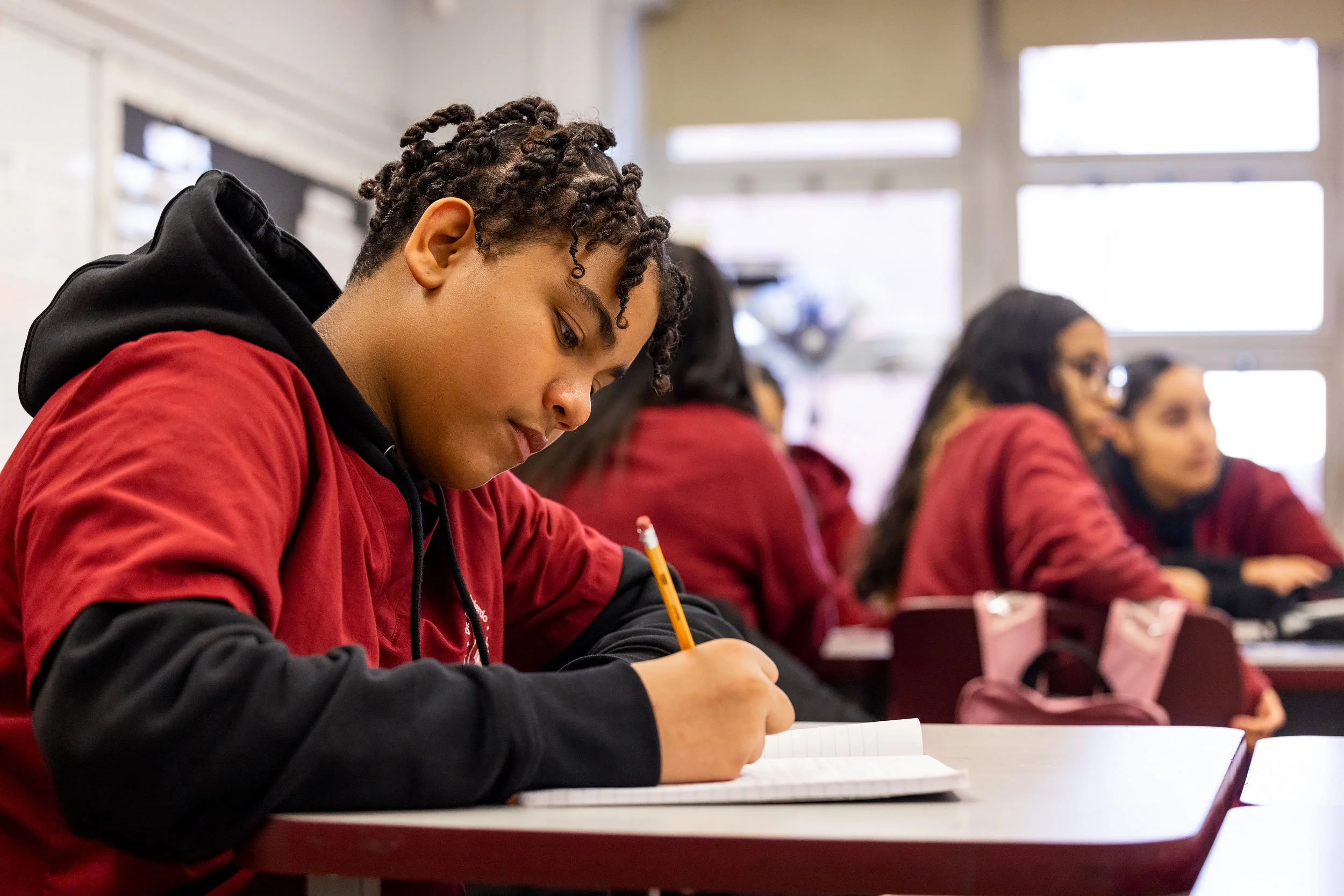 Student writing in notebook during independent study time.