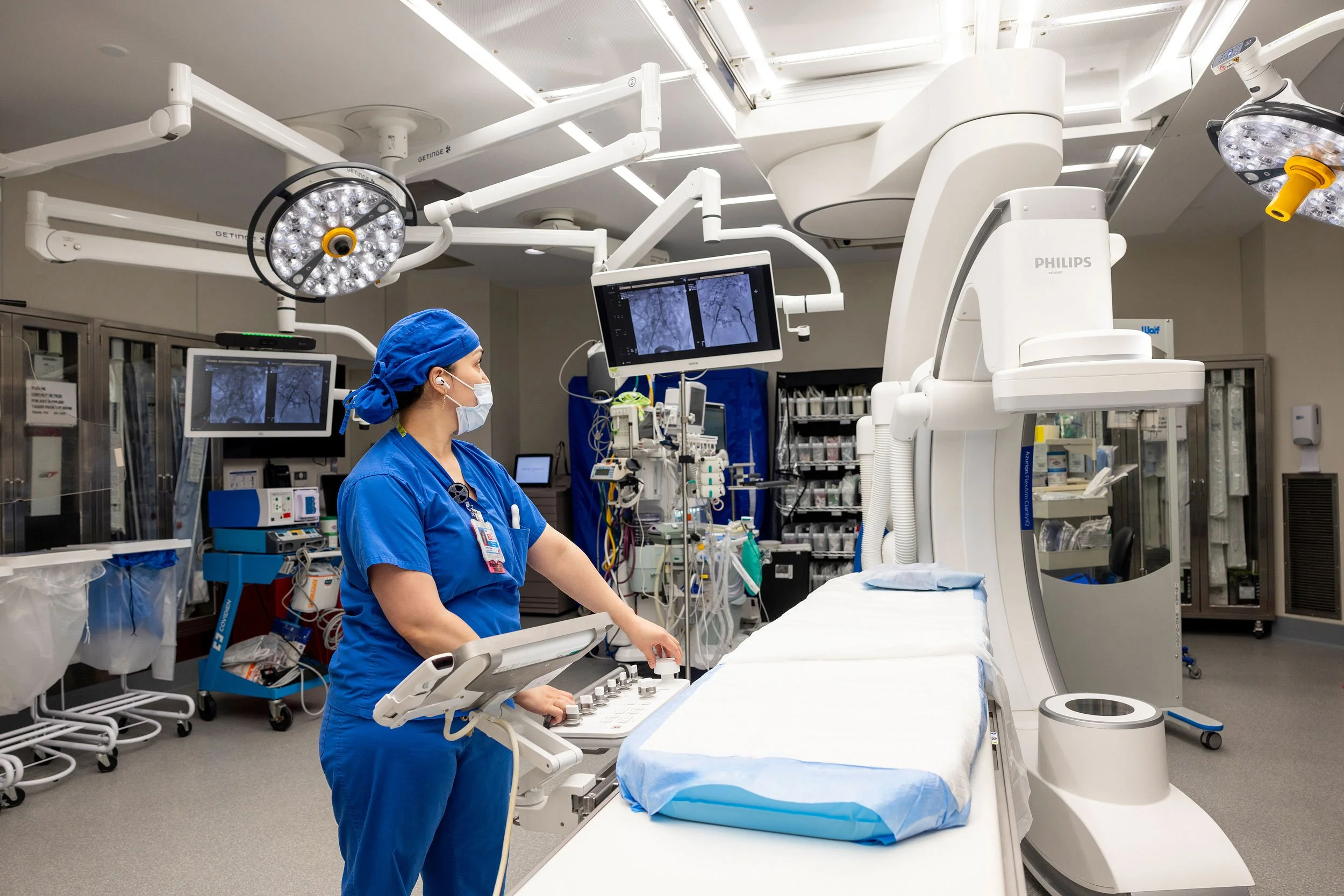 Female healthcare worker in blue scrubs preparing an operating room.