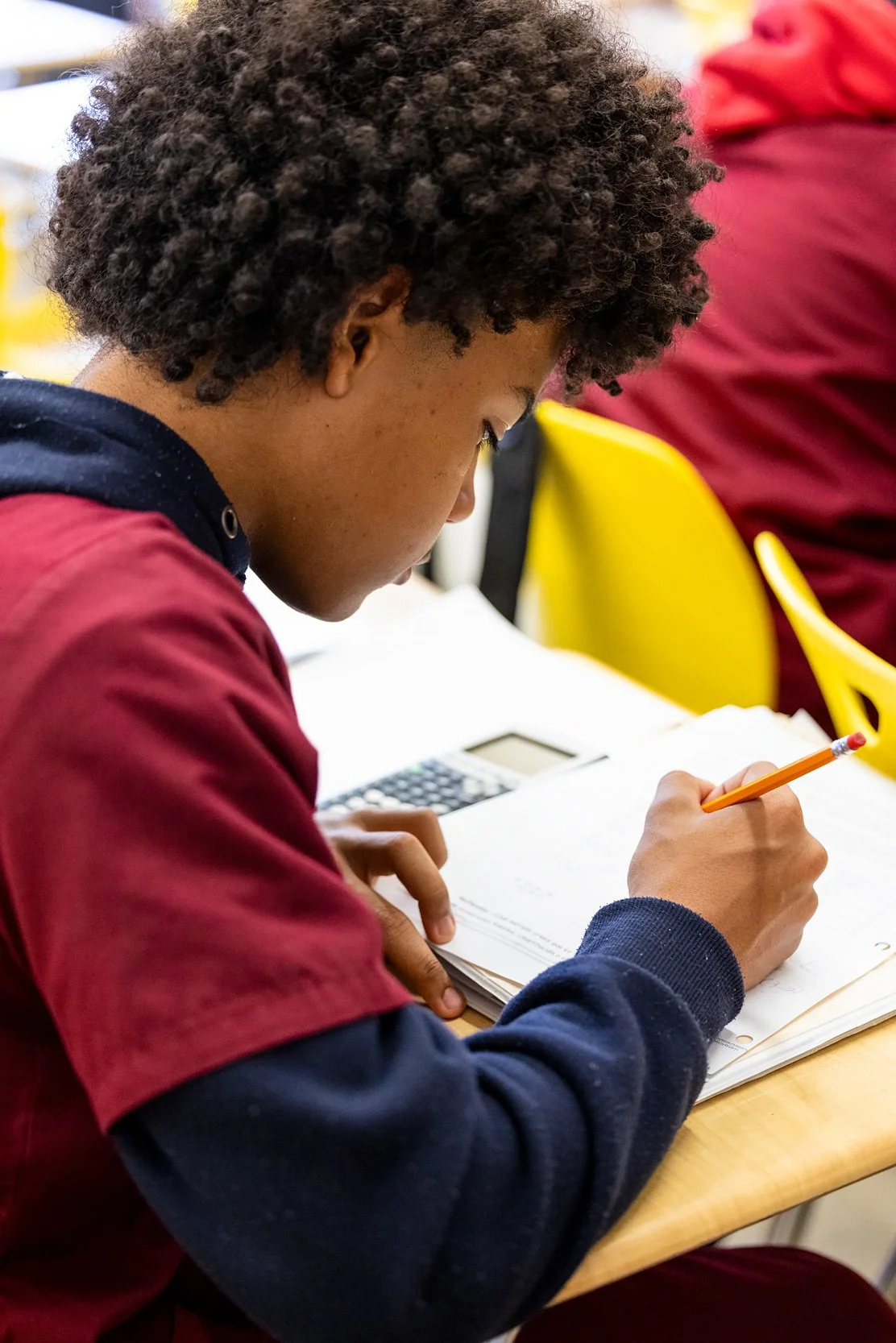 Close-up of student writing with pencil, focused on schoolwork.