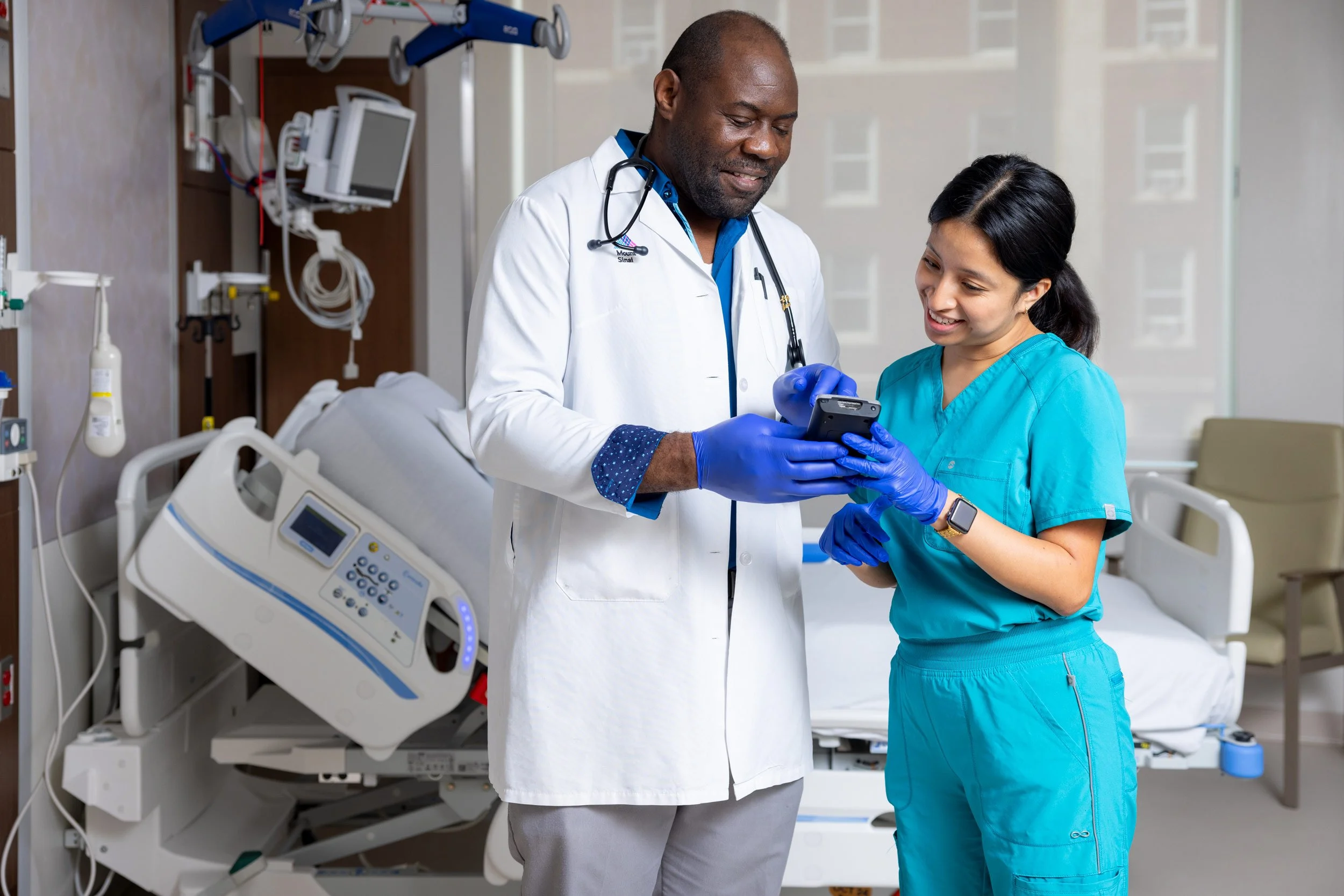 Two medical professionals using a tablet beside a patient in recovery.