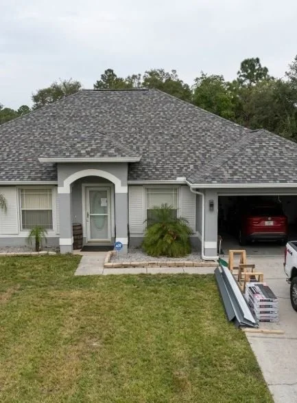 A single-story gray house in Homosassa, Florida, featuring a clean architectural shingle roof.