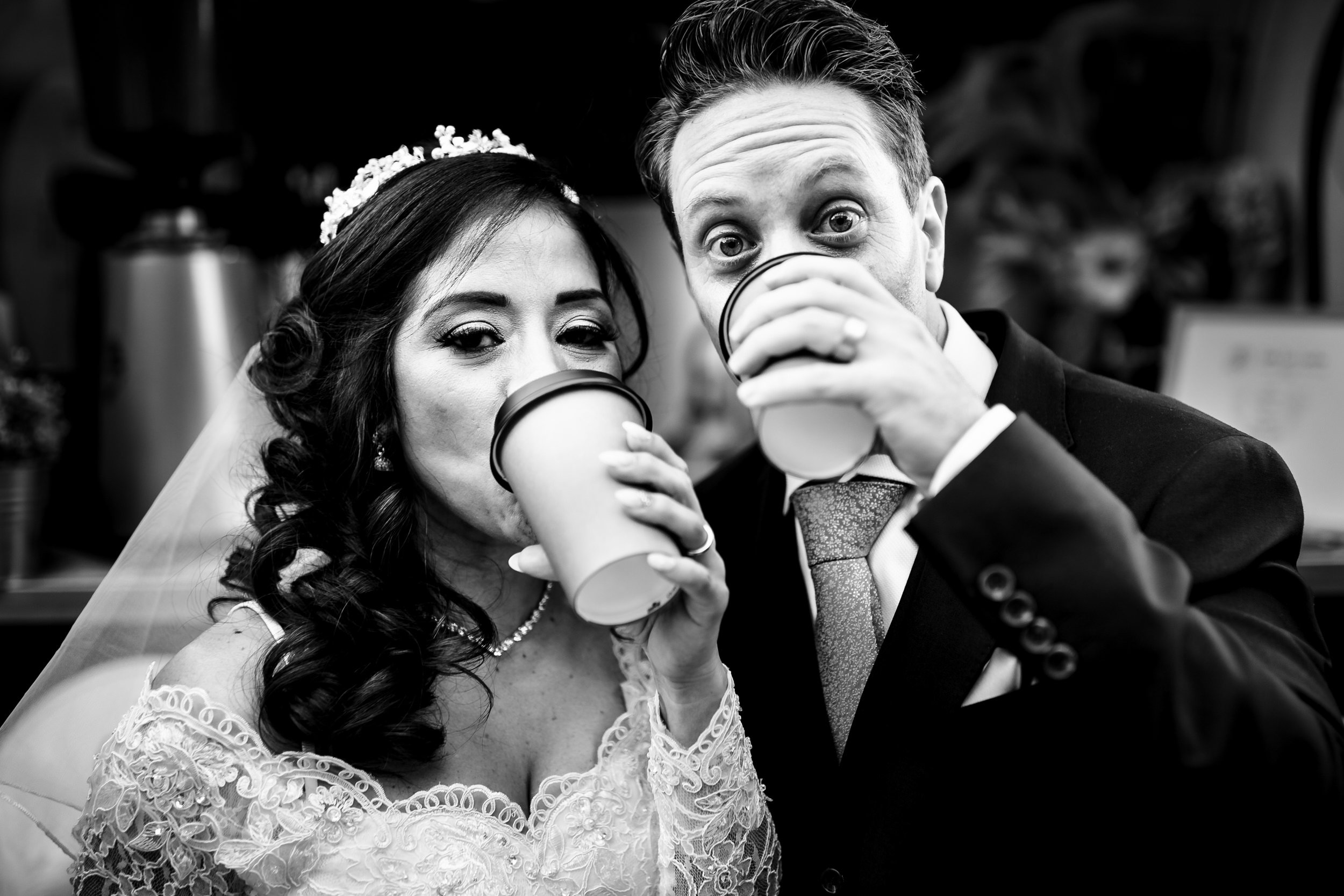 Black and white photo of a Hunter Valley bride and groom drinking out of coffee cups, looking at the camera, after the wedding ceremony.