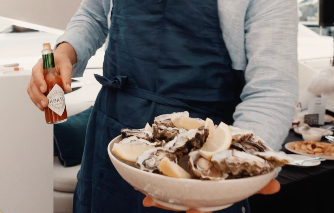Oysters served on ice by a waiter also holding Tabasco sauce