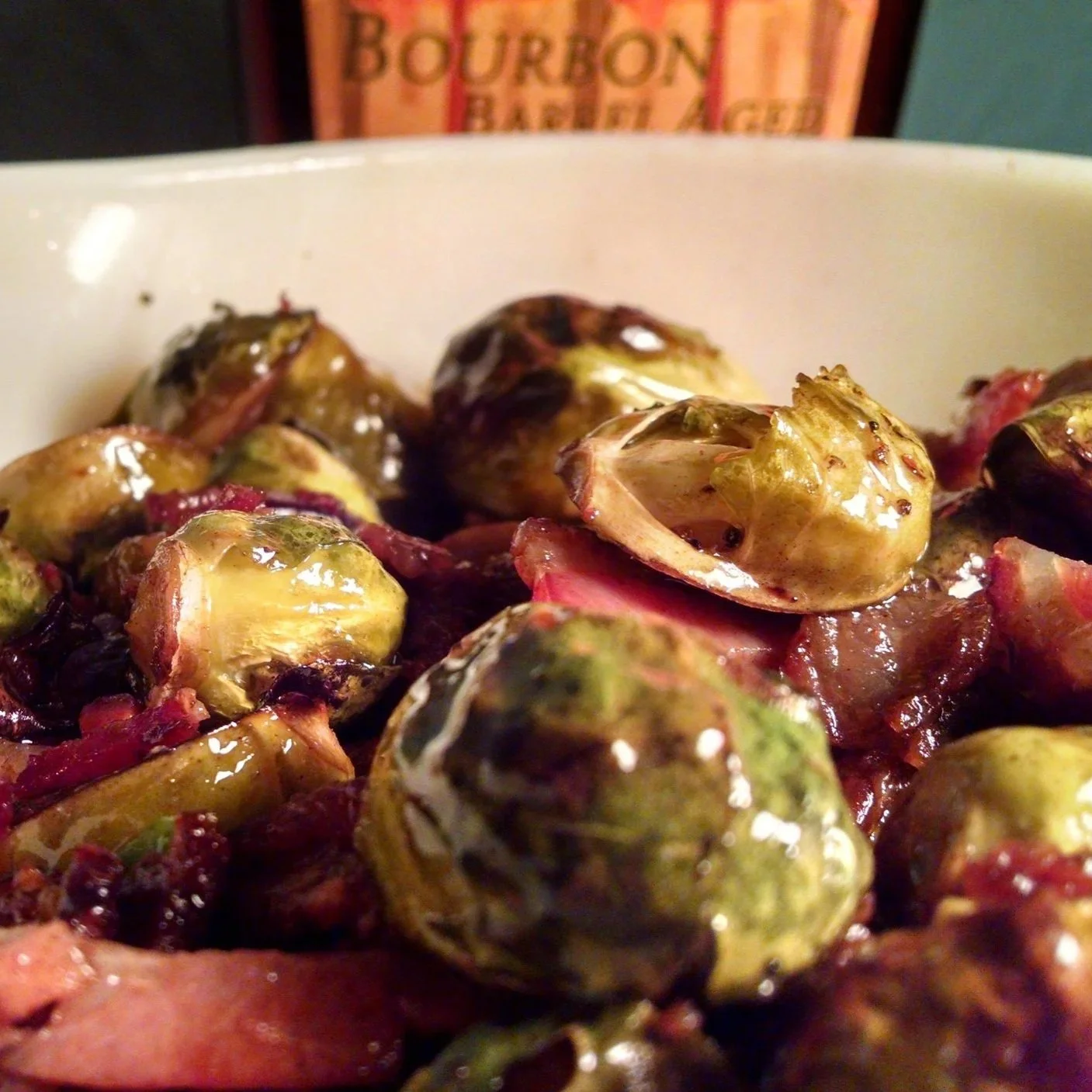 Close-up of roasted Maple Bacon Brussels sprouts with caramelized bacon in a white dish.