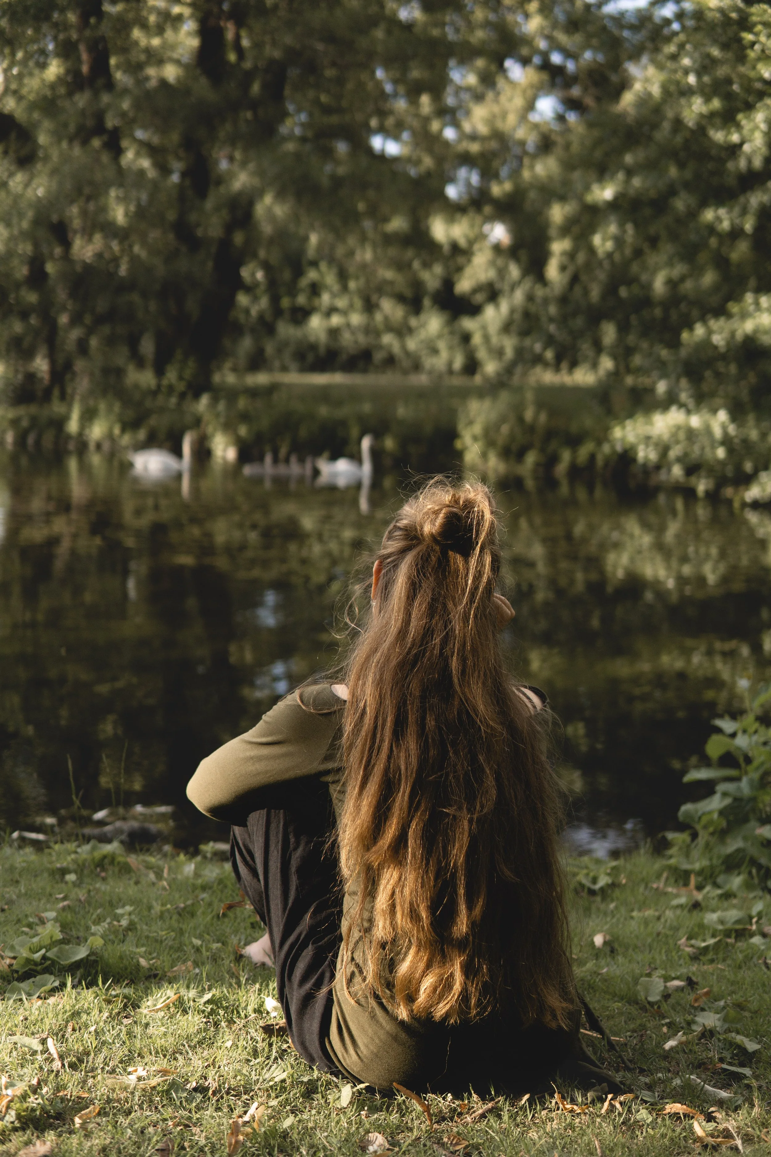 Eine Person sitzt im Freien auf einem Stein, sammelt getrocknete Blumen und Pflanzen zur Herstellung von Naturmaterialien.