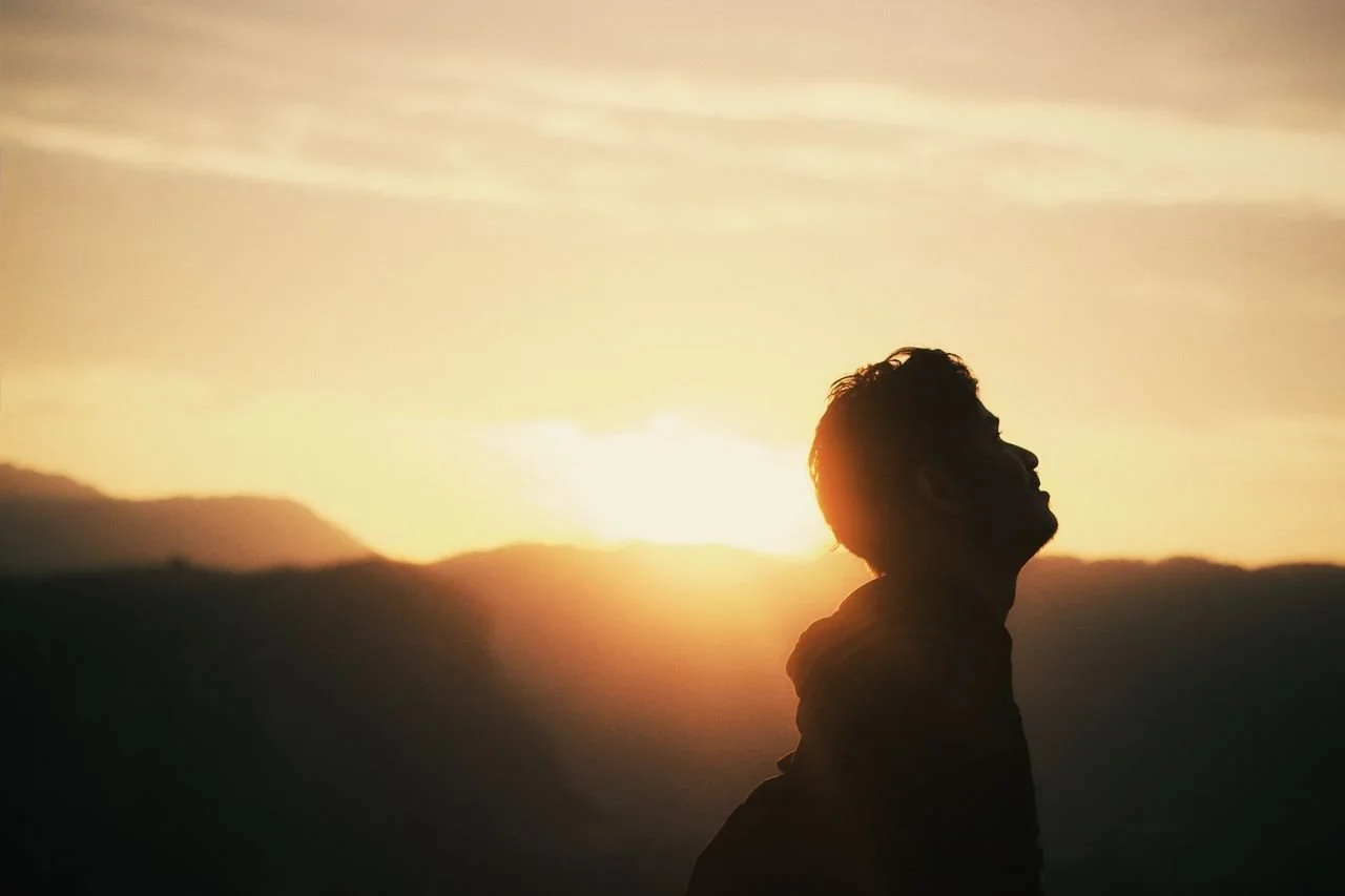 silhouette-of-anonymous-traveler-enjoying-bright-sunset-in-mountains