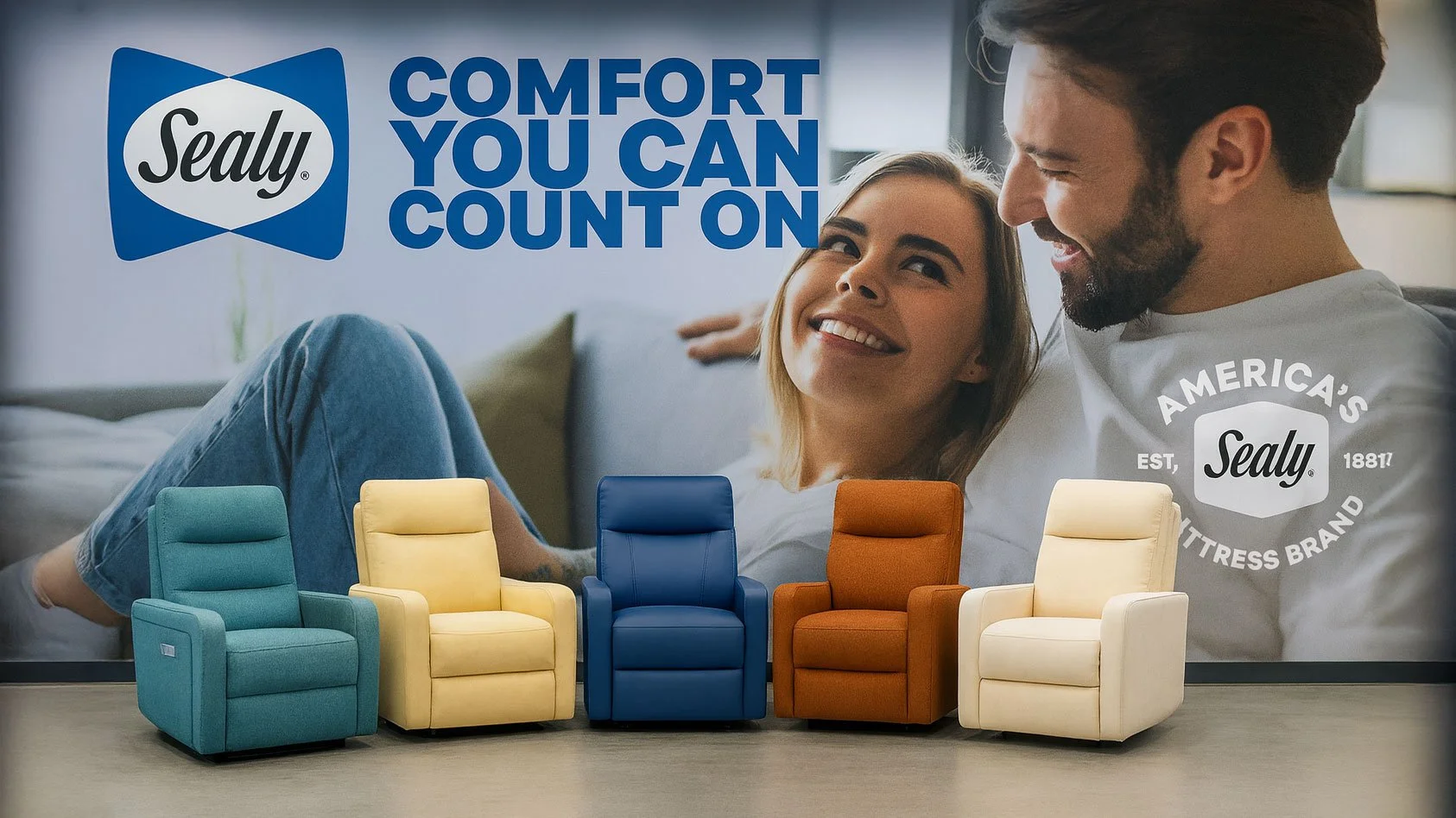 Five armchairs in teal, yellow, blue, orange, and ivory lined up in front of a Sealy mattress advertisement featuring a smiling couple on a bed. The ad reads "Sealy COMFORT YOU CAN COUNT ON" and includes the Sealy logo with the text "America's Mattress Brand".