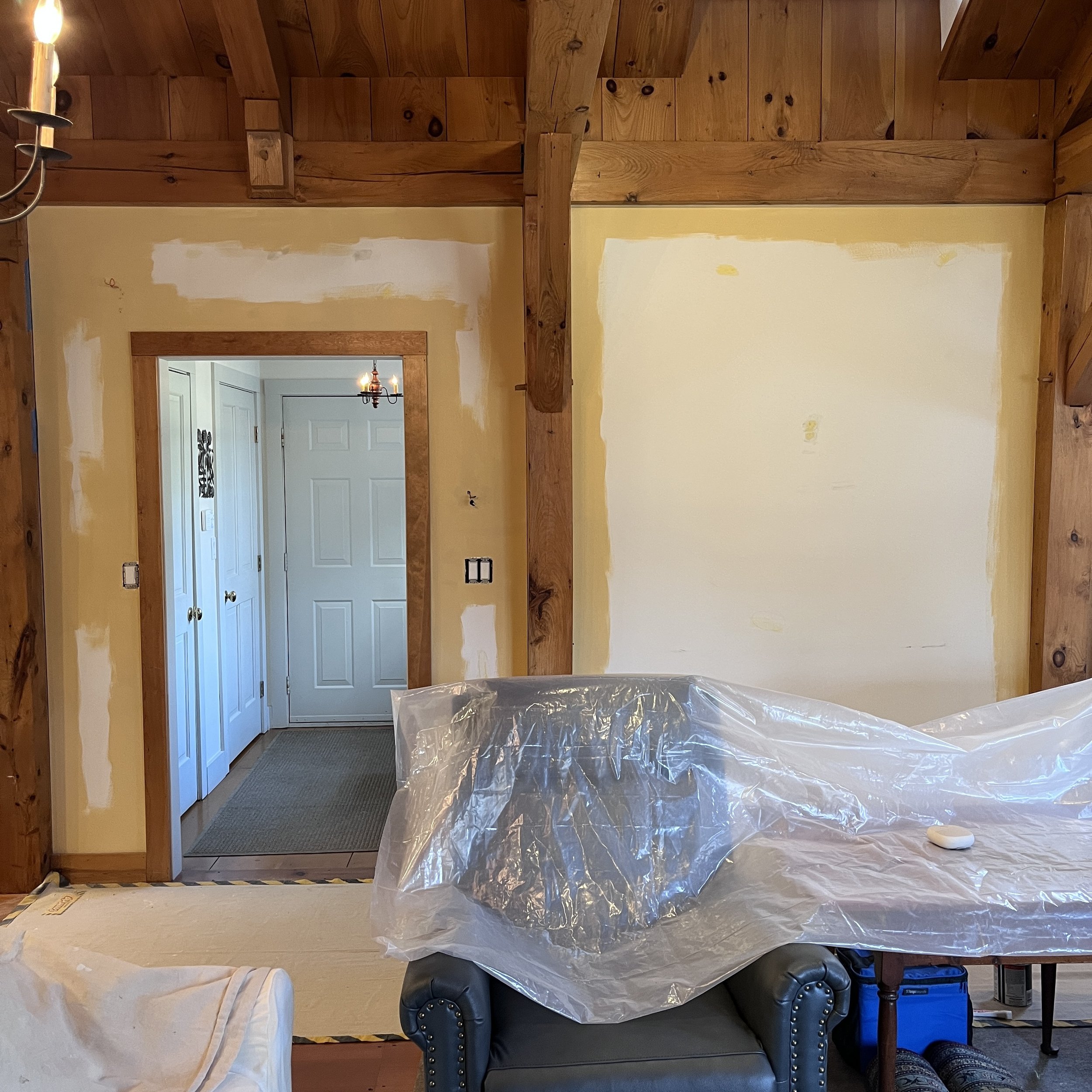 Interior of a room under renovation with wooden beams, walls being painted, furniture covered with plastic, and a view into an adjacent room with a closed white door.Home show kitchen floors checkerboard faux painted floor venetian plaster metallic d