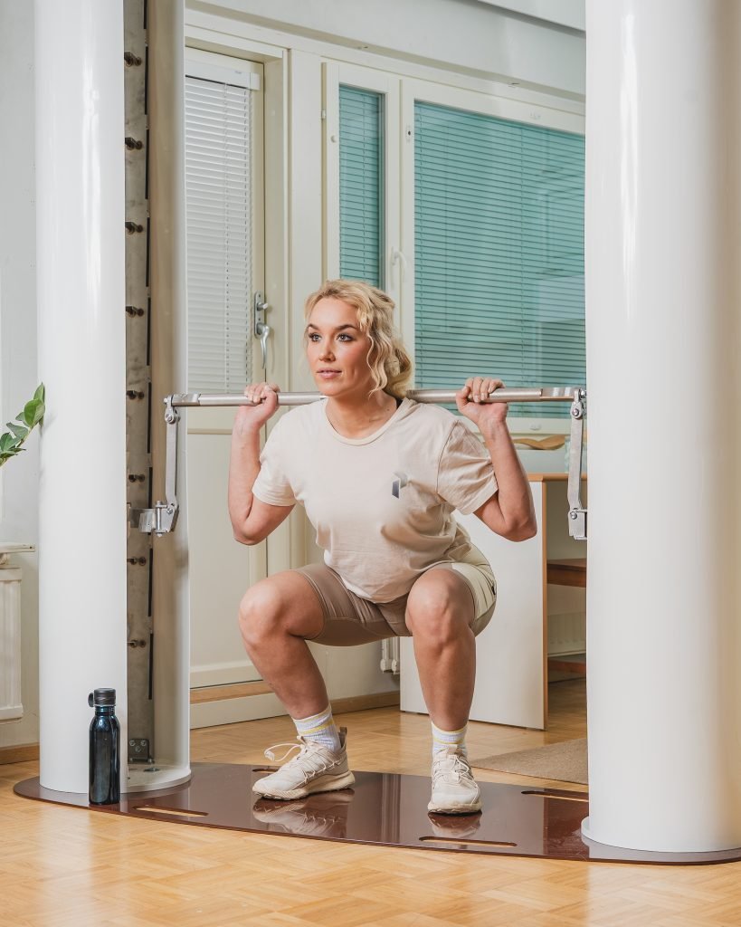 Person doing squats with a barbell in a gym setting.