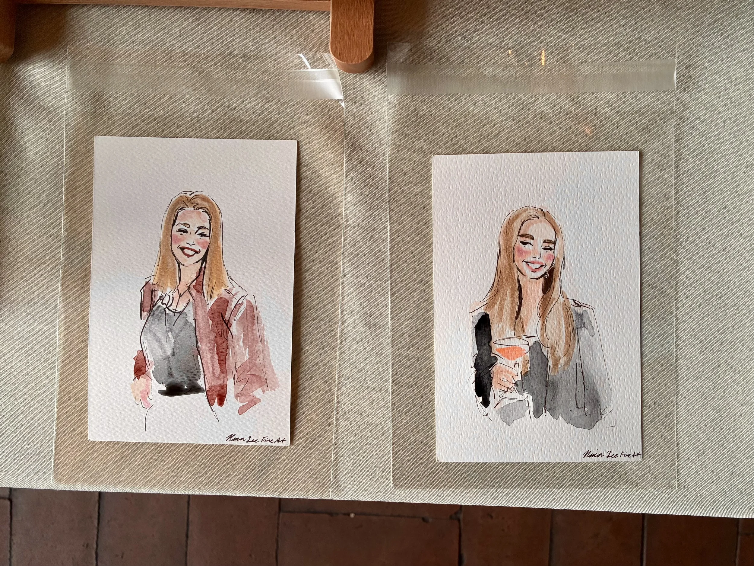 Two live watercolor paintings of woman with long hair, smiling, each holding a drink. Both are signed by the artist, Nina Lee Fine Art. Painted in Chicago IL