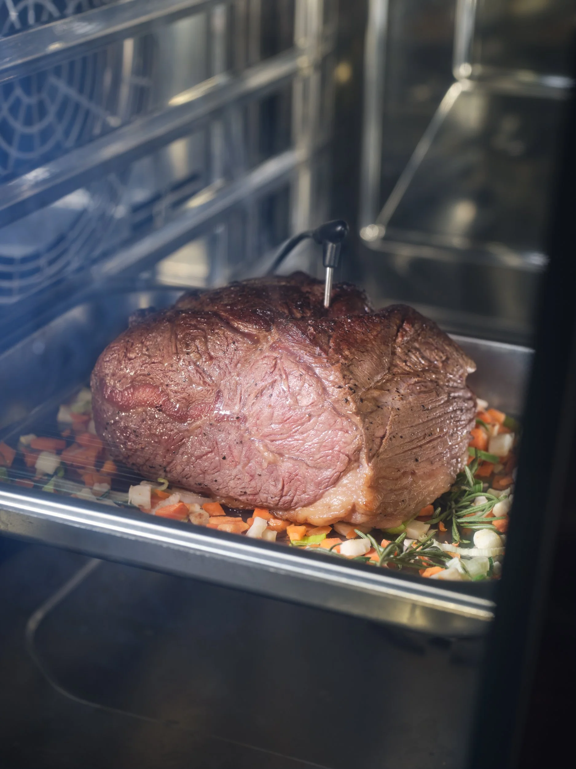 Großes, saftiges Stück Rindfleisch im Ofen, garniert mit Gemüse und Kräutern