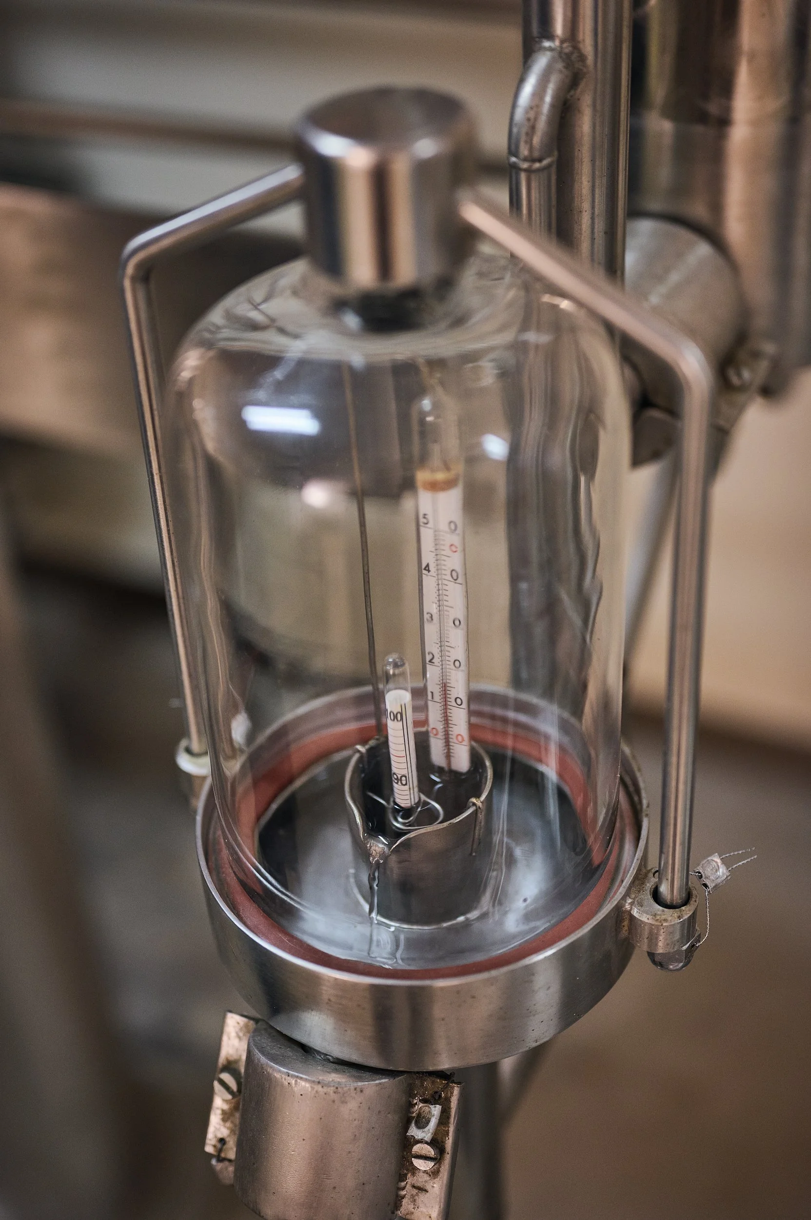 Zwei Glasflaschen mit Temperaturmesser im Inneren, in einer Metallmaschine, wahrscheinlich in einem Labor oder einer industriellen Umgebung.