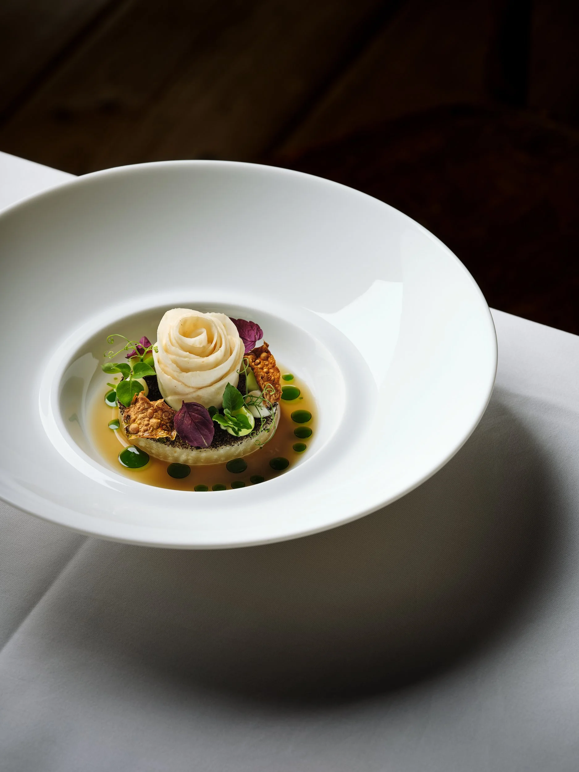 Elegantes Gericht mit Coleslaw in einem weißen Schüssel, garniert mit Microgreens und Mini-Kräutern, serviert auf weißem Tischtuch.