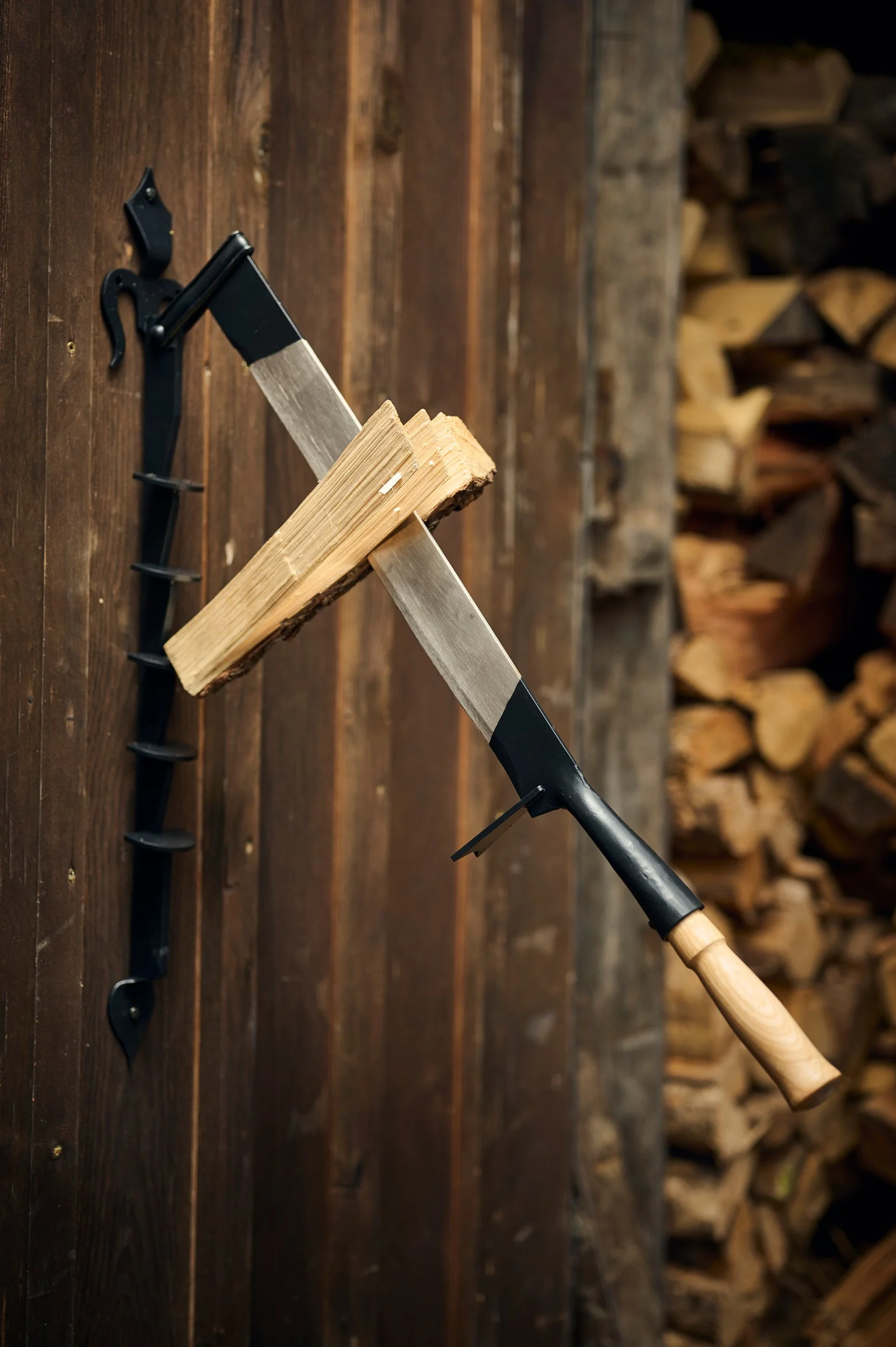 Axe mounted on a wooden wall with chopped wood in the background.