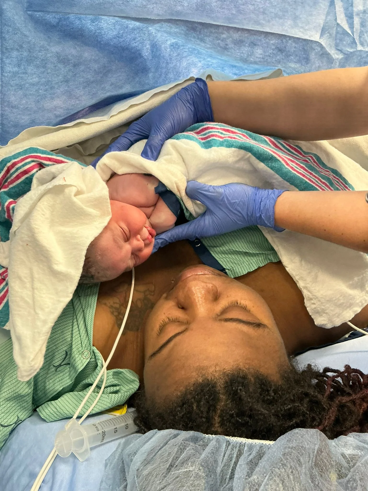 A person lying on a hospital bed, having just given birth, with a newborn baby swaddled in a blanket on their chest, the moment everyone waits for. BUt what happens after birth?