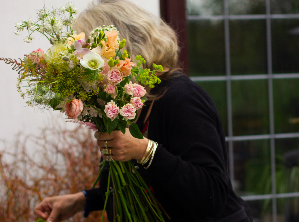A bouquet of blue, white, and green flowers arranged in a paper wrapper.