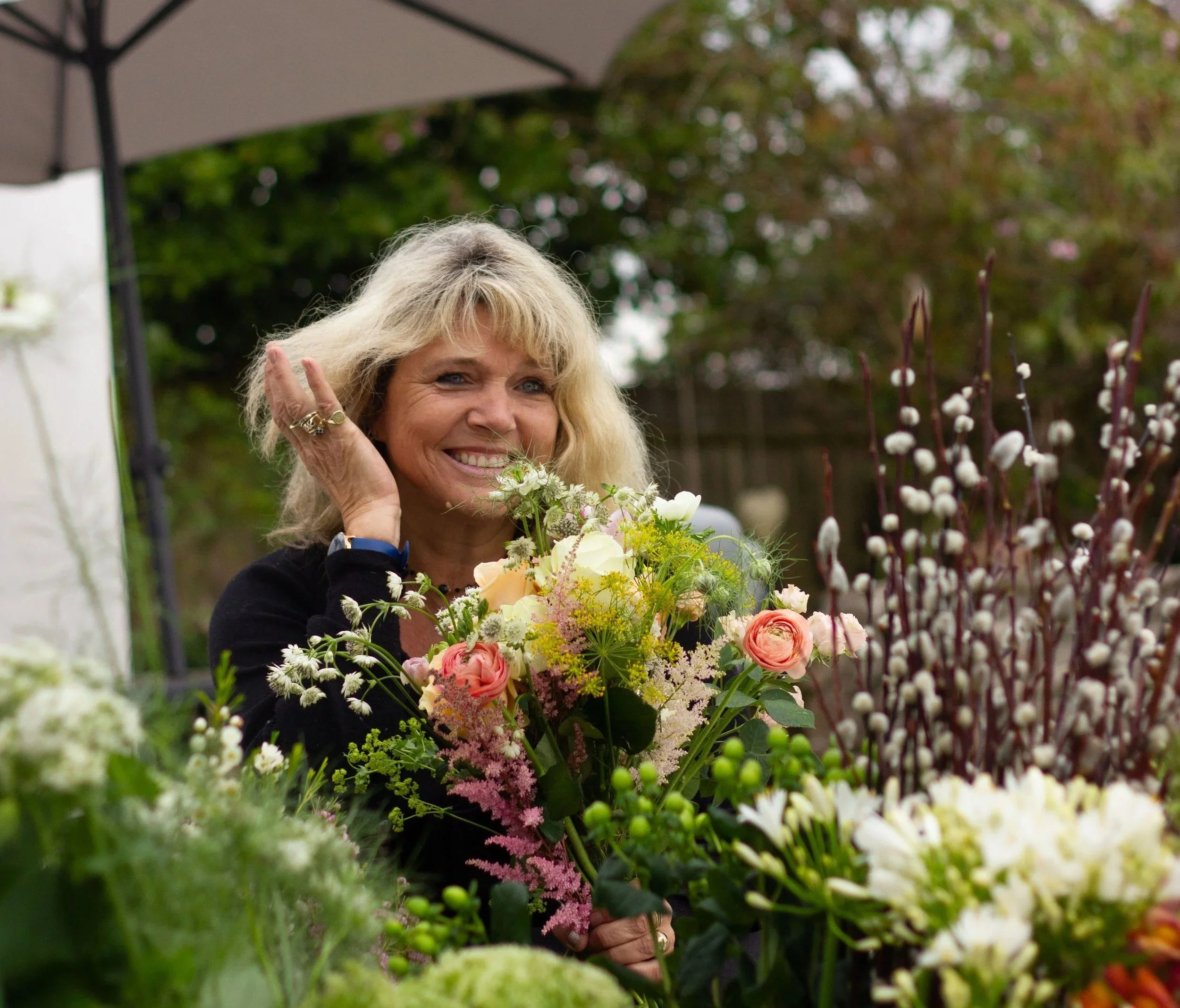 Arrangement of dried and fresh flowers, including lavender, pink and orange pampas grass, yellow, purple, and red berries, in glass vases against a plain white background.