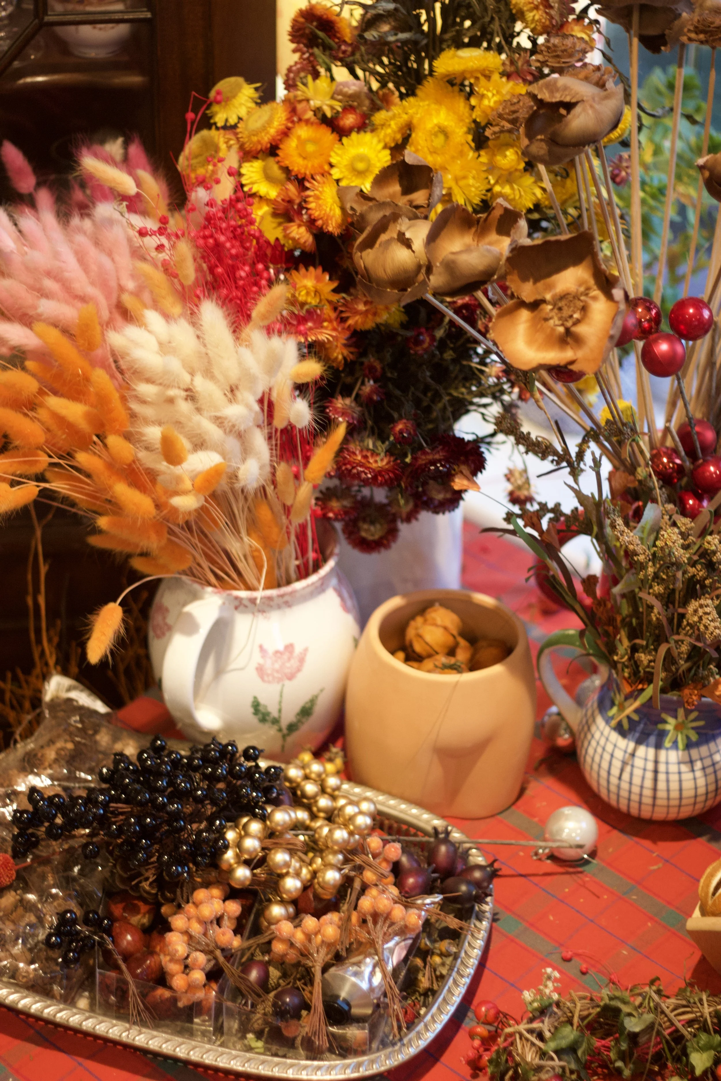 Arrangement of dried flowers, berries, and decorations in vases and on table.