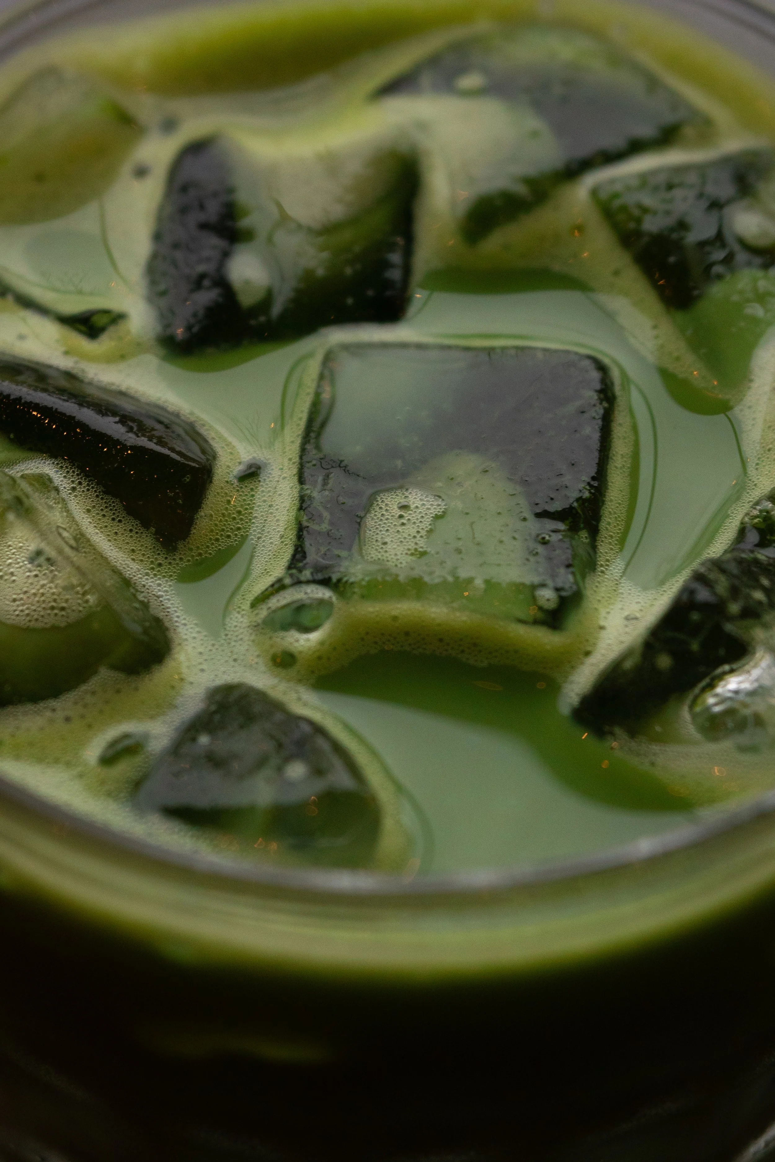 Close-up of a green beverage with ice cubes.
