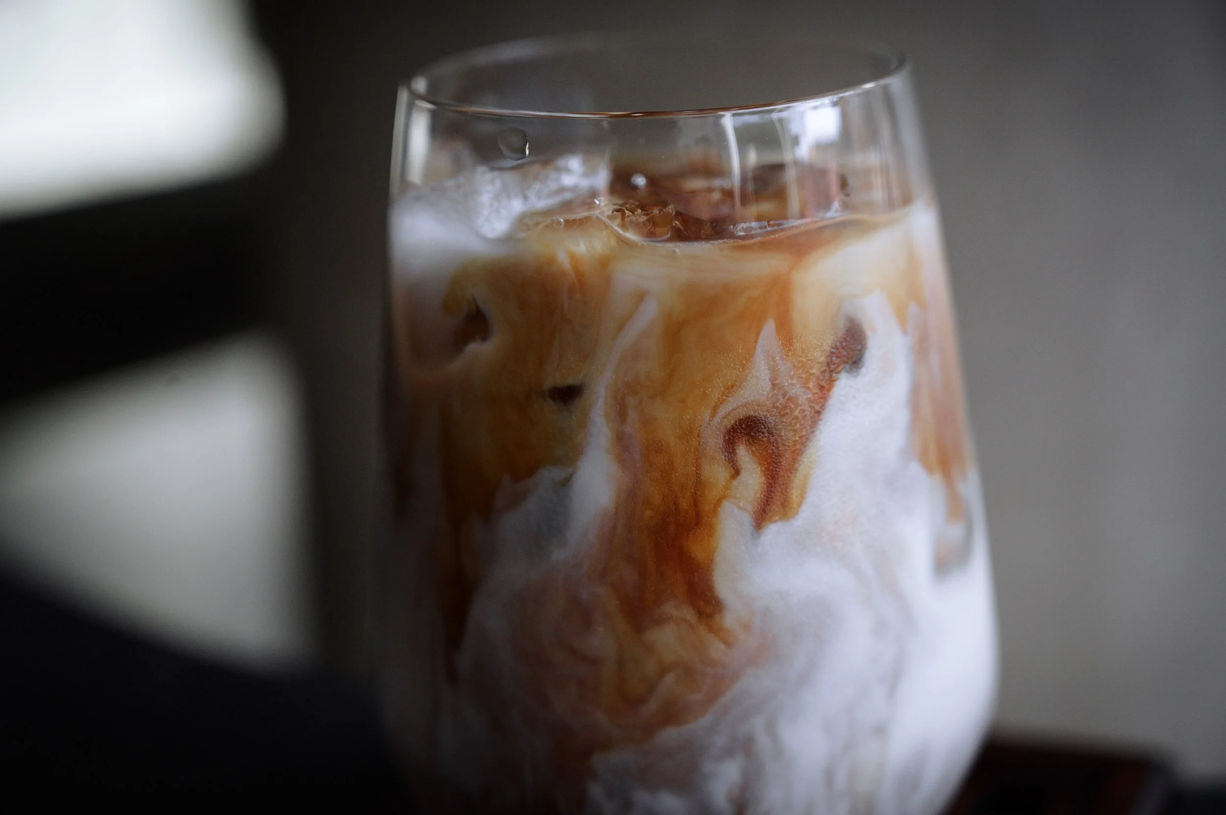 Glass of iced coffee with cream swirling inside