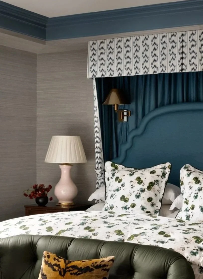 Elegantly decorated bedroom with a blue upholstered bed, floral bedding, and green sofa. Matching curtains and lamps on bedside tables add to the sophisticated decor.