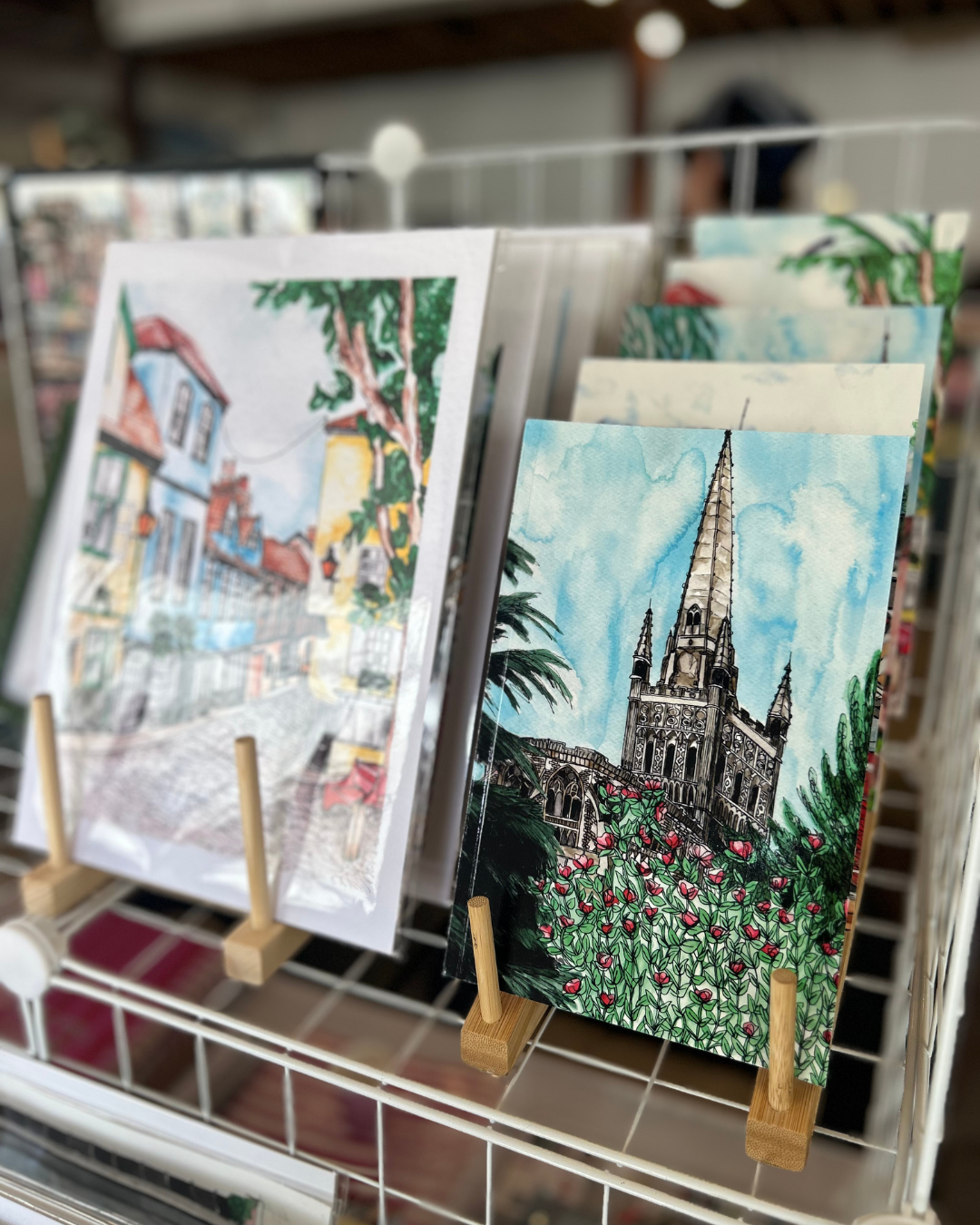 Greeting cards on display: one with a church illustration, others with street scenes.