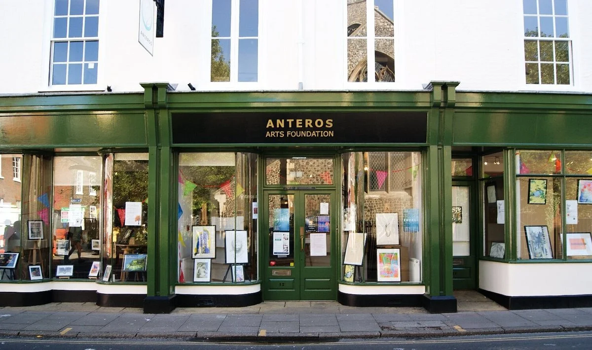 Front view of Anteros Arts Foundation with green trim, displaying framed artworks in windows.