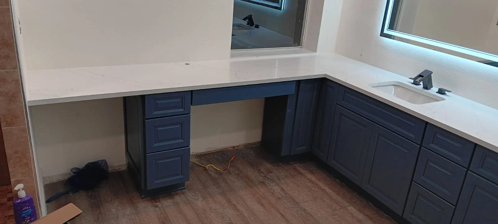 Under construction or renovation kitchen with dark blue cabinets, a white countertop, and a sink, with no appliances installed yet.