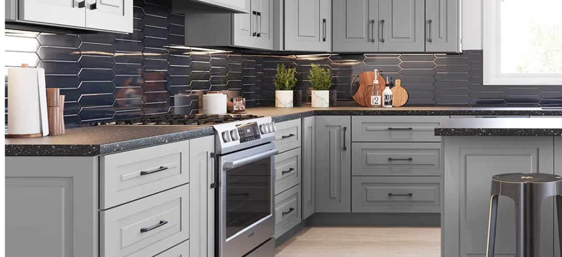 Modern kitchen with gray cabinets, black hexagonal tile backsplash, stainless steel oven, black stools, and decorative items on the countertop.