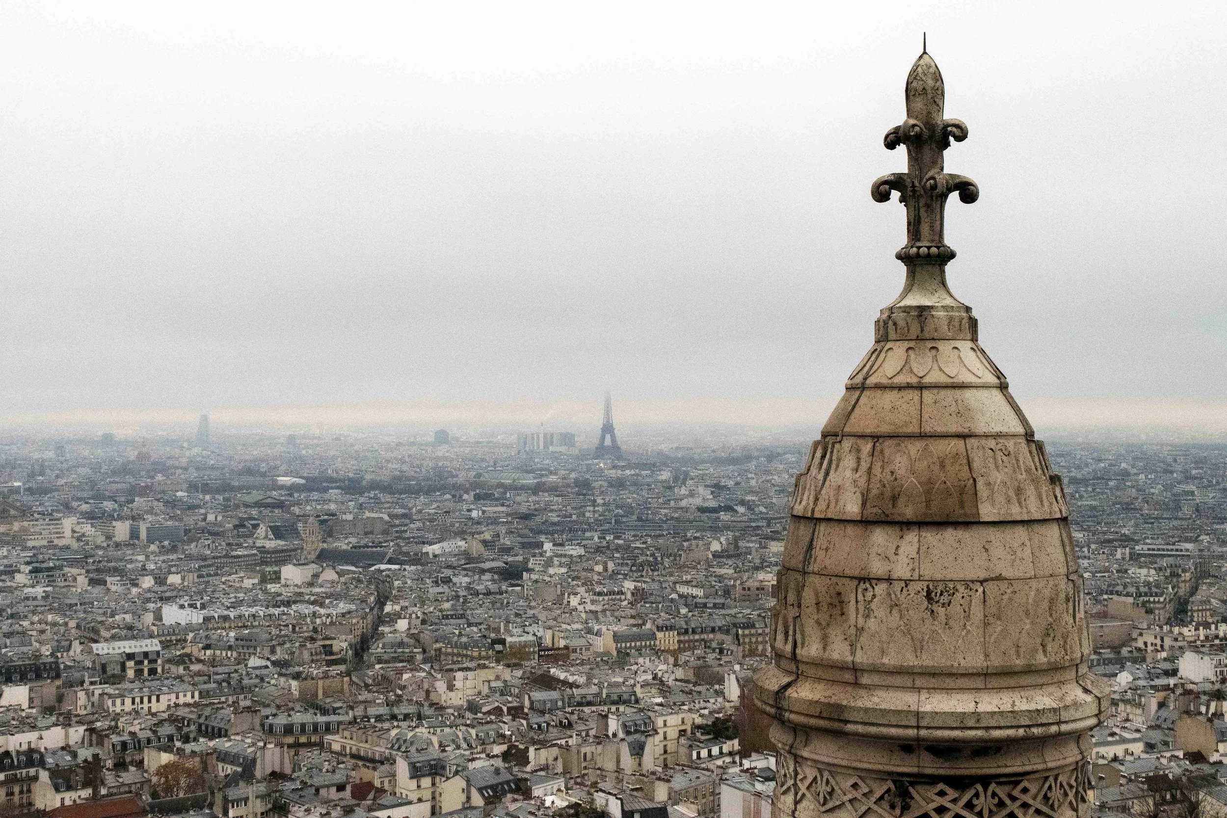 Snow-covered city street lined with parked cars, leafless trees, and apartment buildings under a bright, clear blue sky with the sun shining.