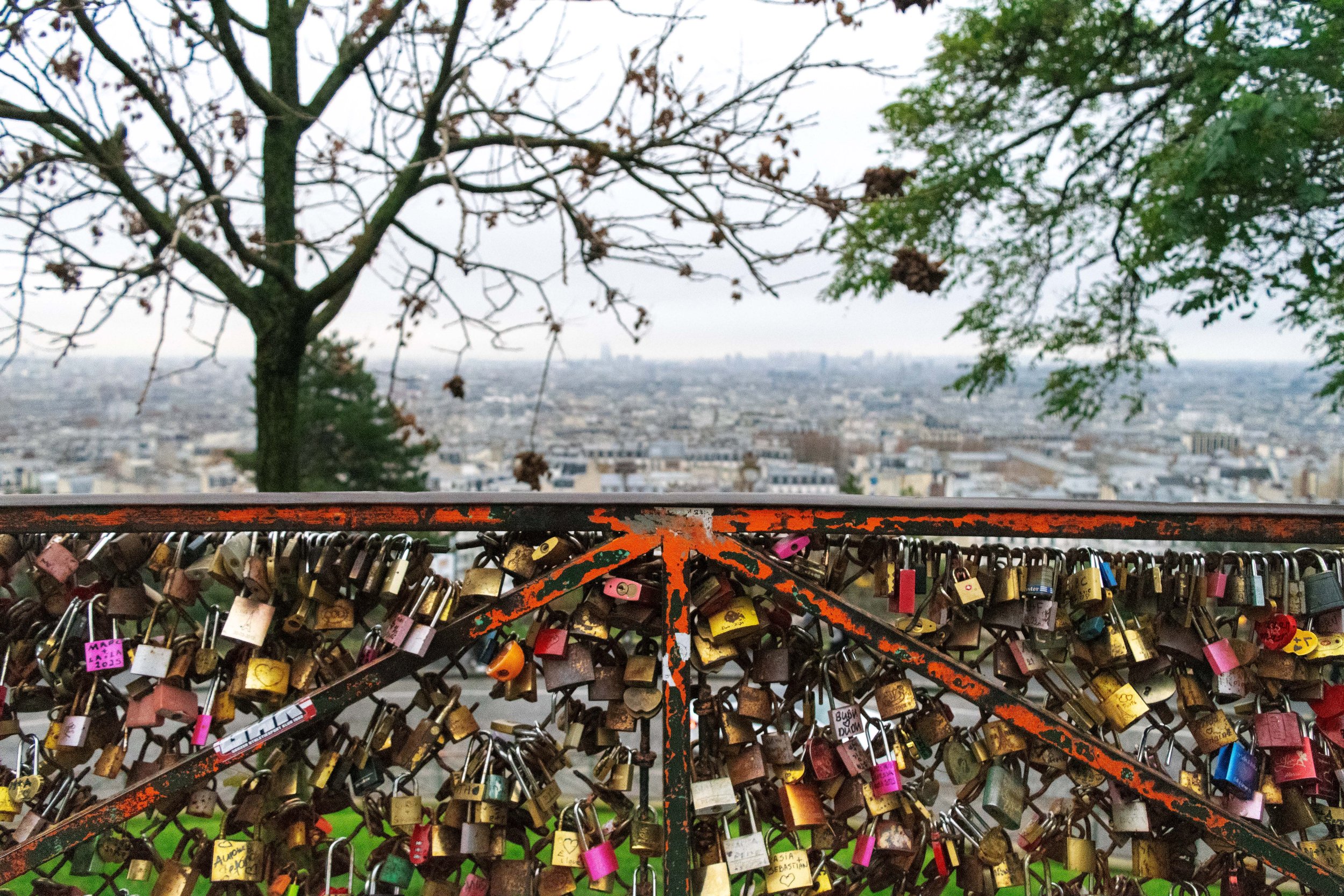 A snow-covered urban street at night with stairs leading to row houses, trees, and streetlights.