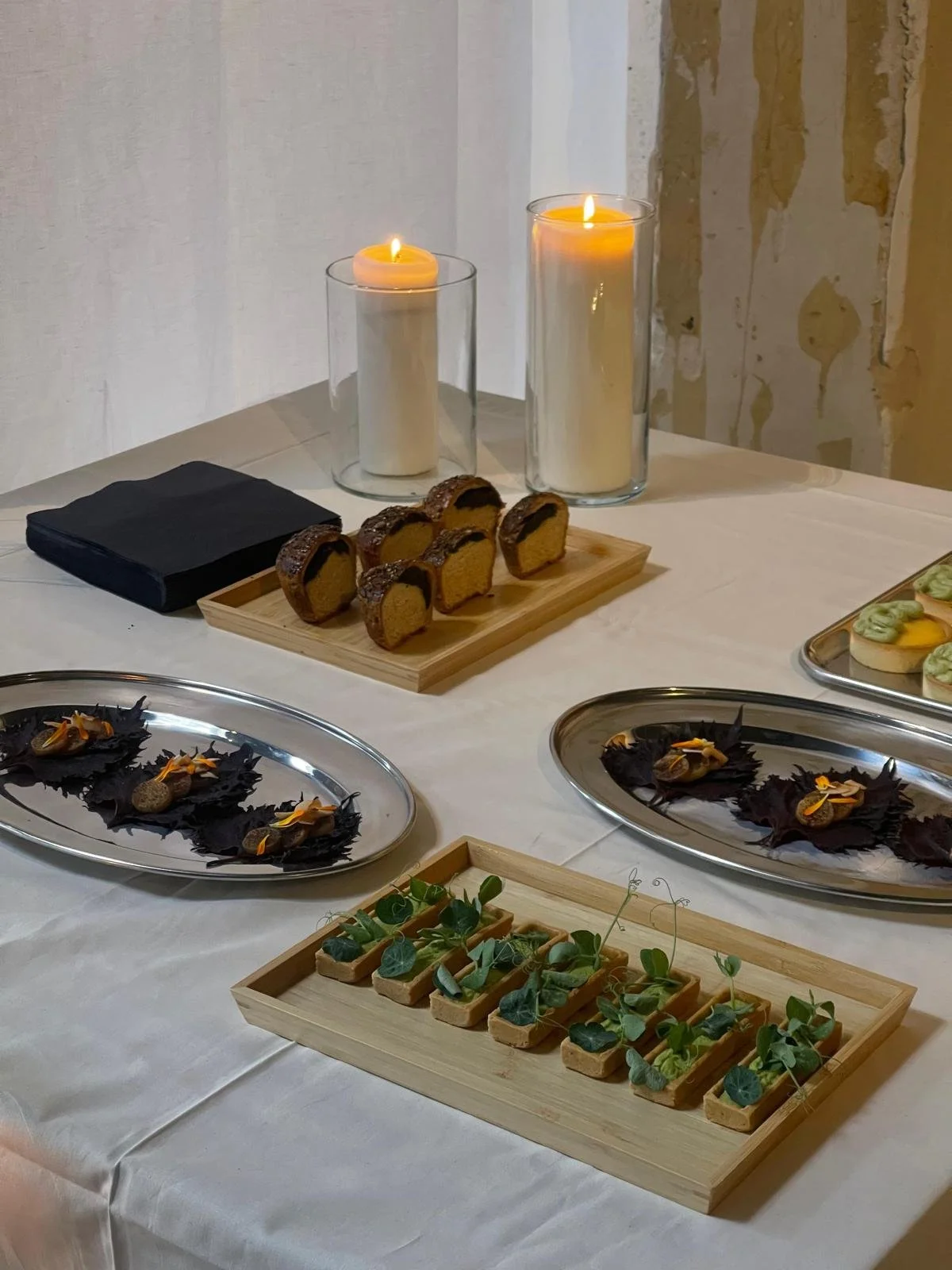 Decoratieve gerechten en kaarsen op een tafel, inclusief hapjes met groene toppings en krokante snacks.