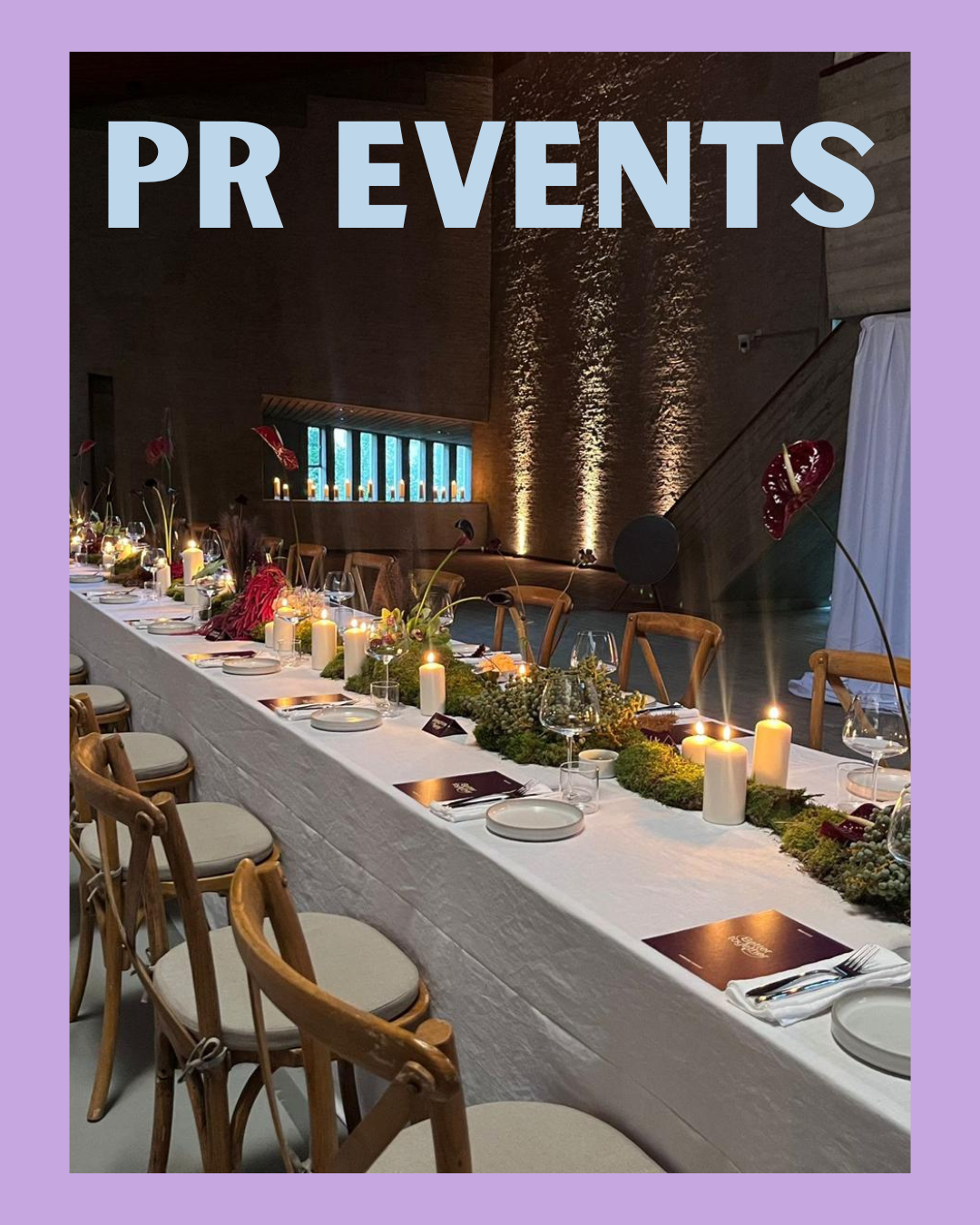 Een lang gedekte tafel voor een event, versierd met kaarsen, bloemen en menu's, in een elegante zaal met zachte verlichting en stenen muren.