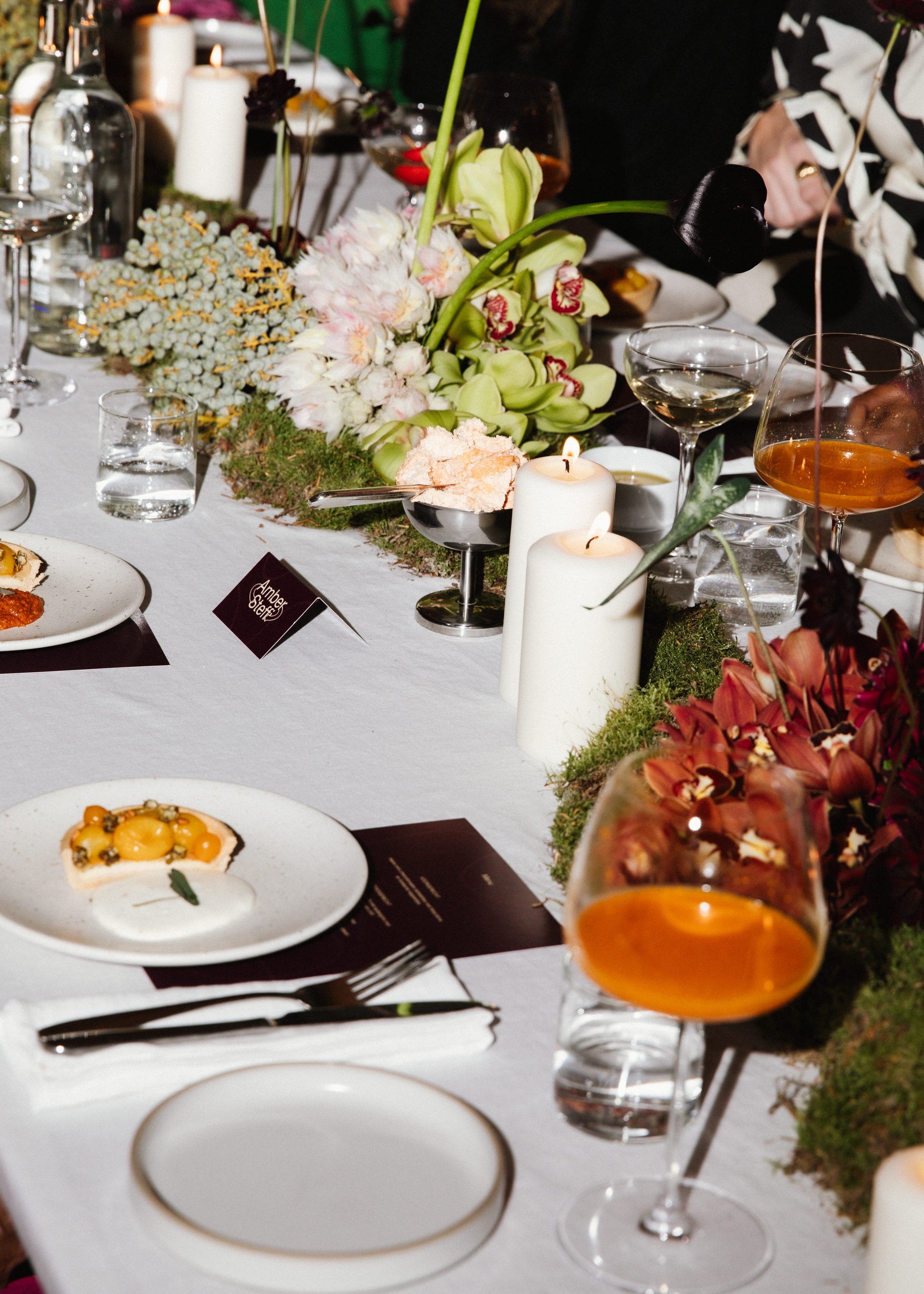 Elegant feesttafel met bloemstukken, kaarsen, glazen wijn en dessert, decoratie voor een feestelijke gelegenheid.