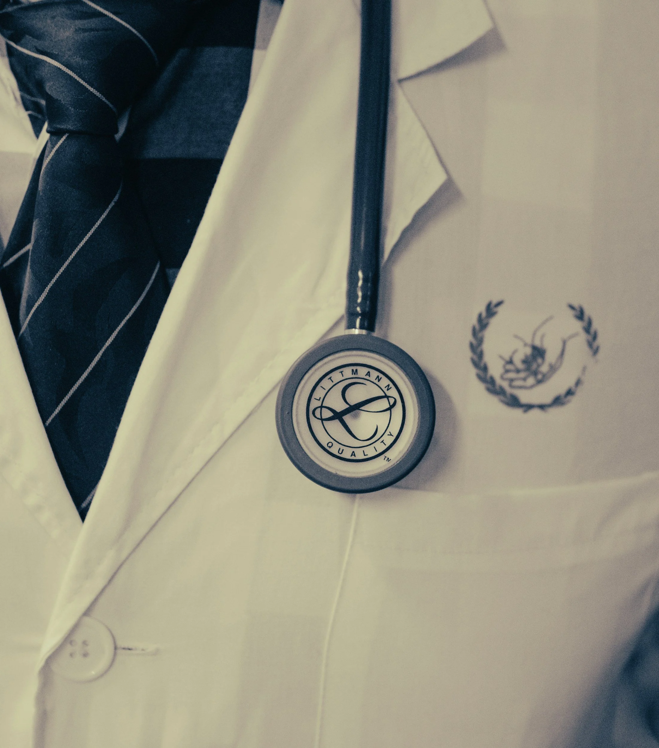 Close-up of a doctor’s white coat with a Littmann stethoscope and a hospital badge.