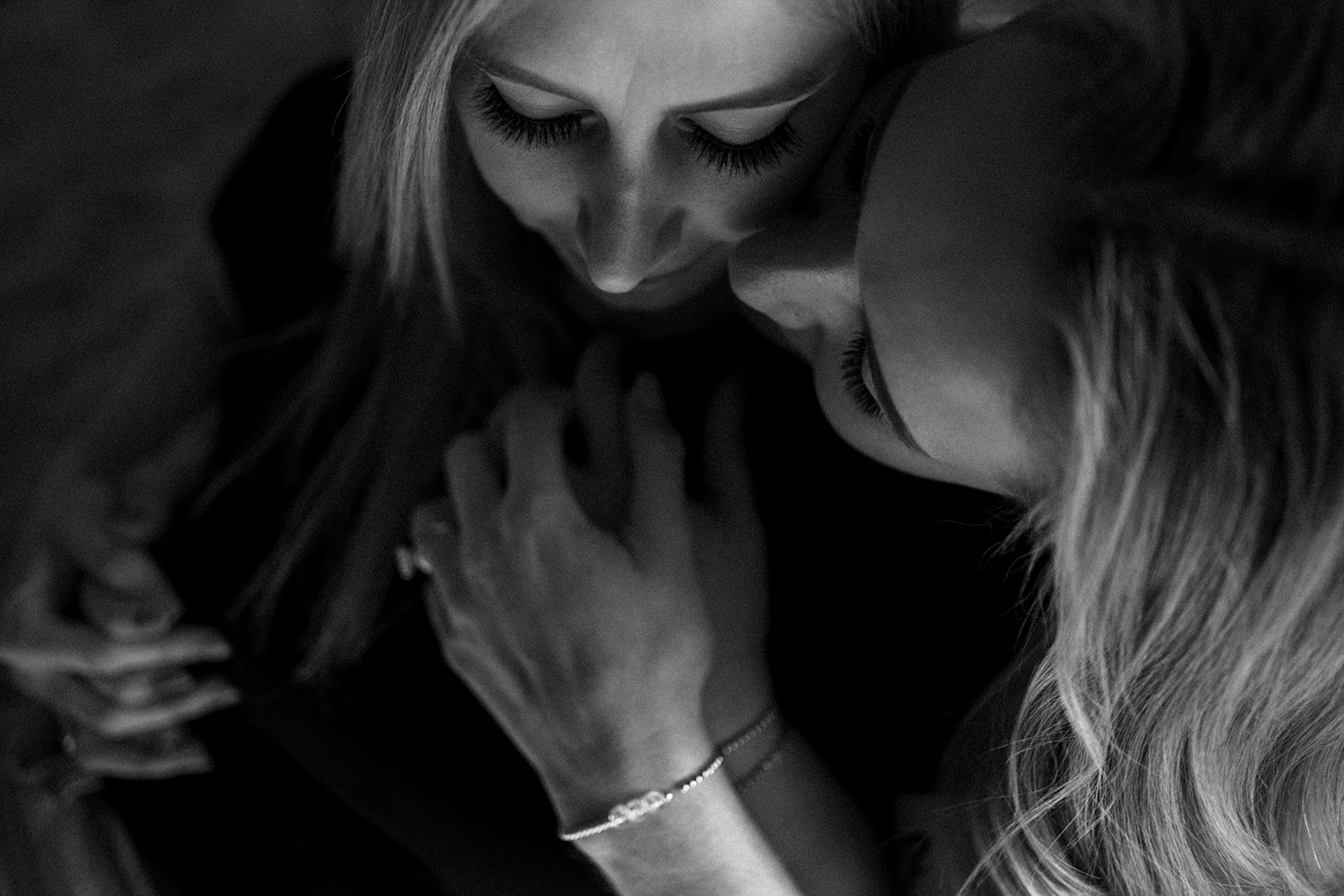 Black and white photo of a couple embracing, faces close and holding hands.