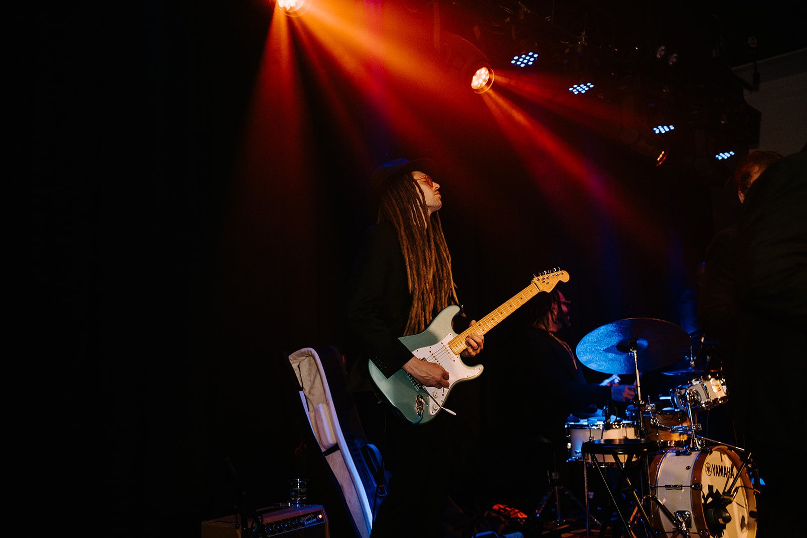Musician playing electric guitar on stage under colorful lights