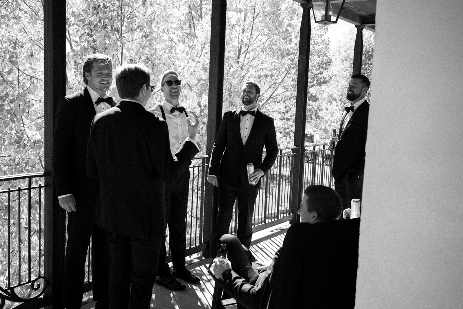 Group of men in formal attire laughing on a balcony
