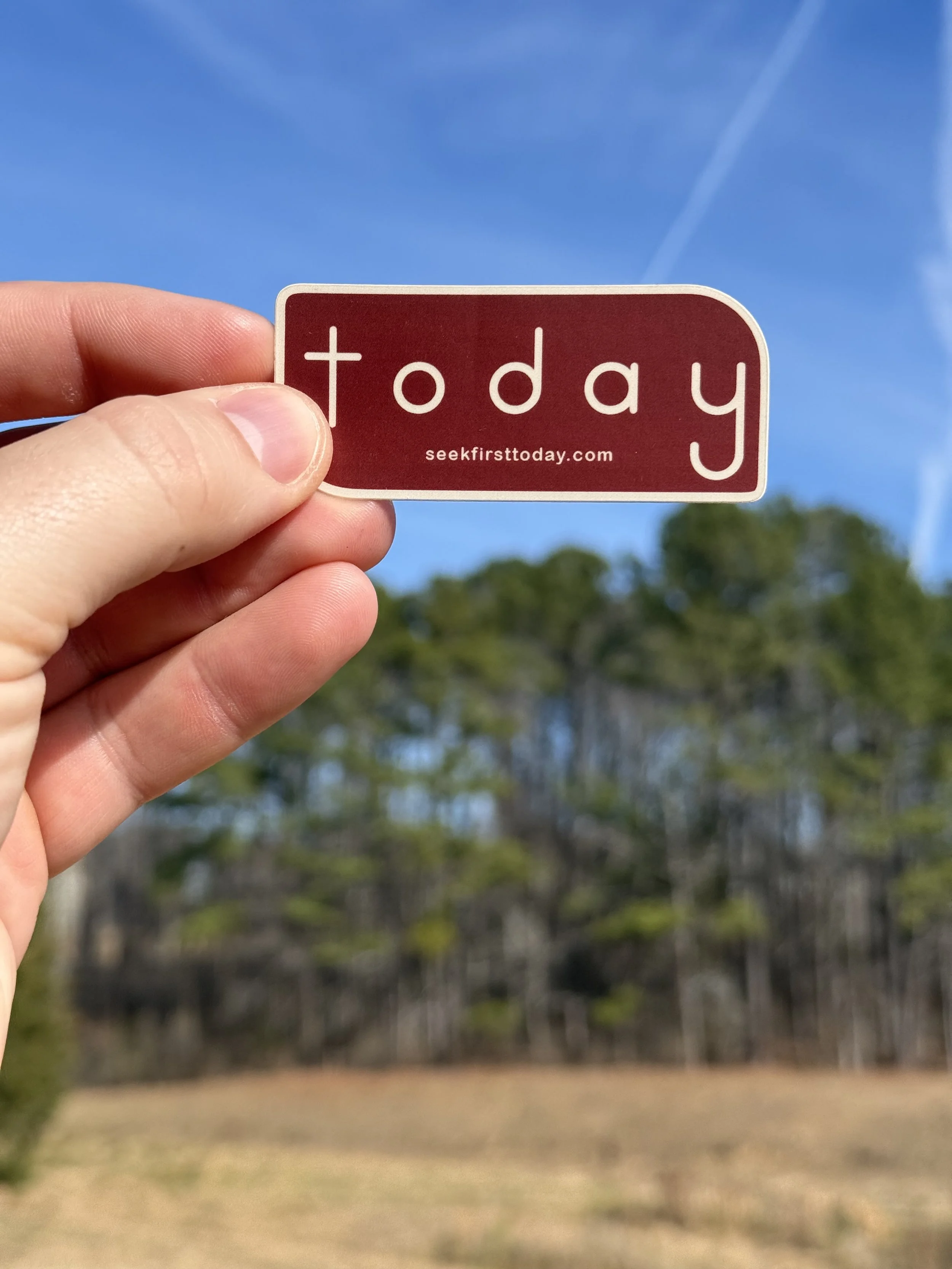 maroon-and-sand-seek-first-today-sticker-with-trees-and-blue-sky-in-background